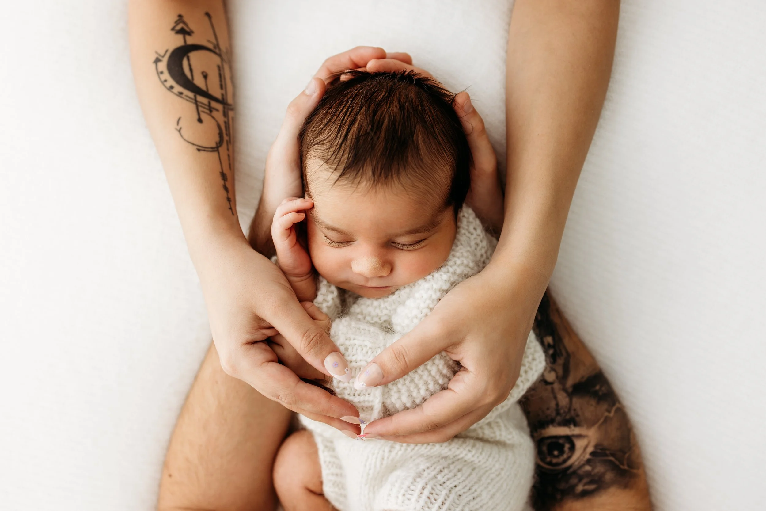 Newborn baby gently cradled in both parents’ hands during a newborn photography session in Perth.