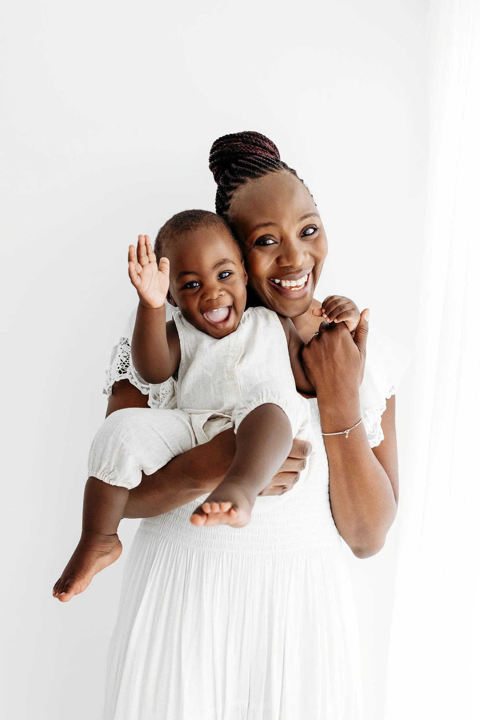 Mum holding her smiling one-year-old during a first birthday portrait session.