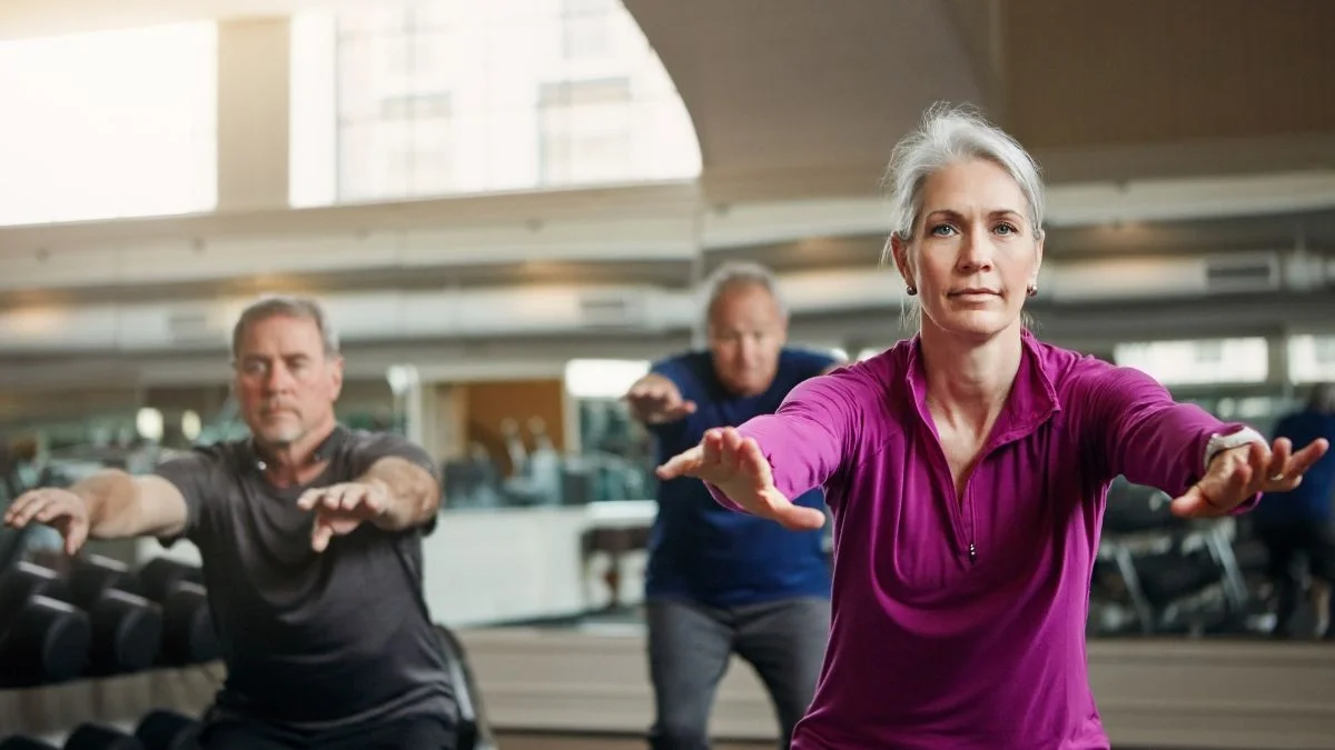 Senior performing air squats in gym