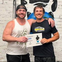 Fight Gravity Fitness client celebrating completion of 200 personal training sessions alongside trainer Nick Butler in the Denver studio.