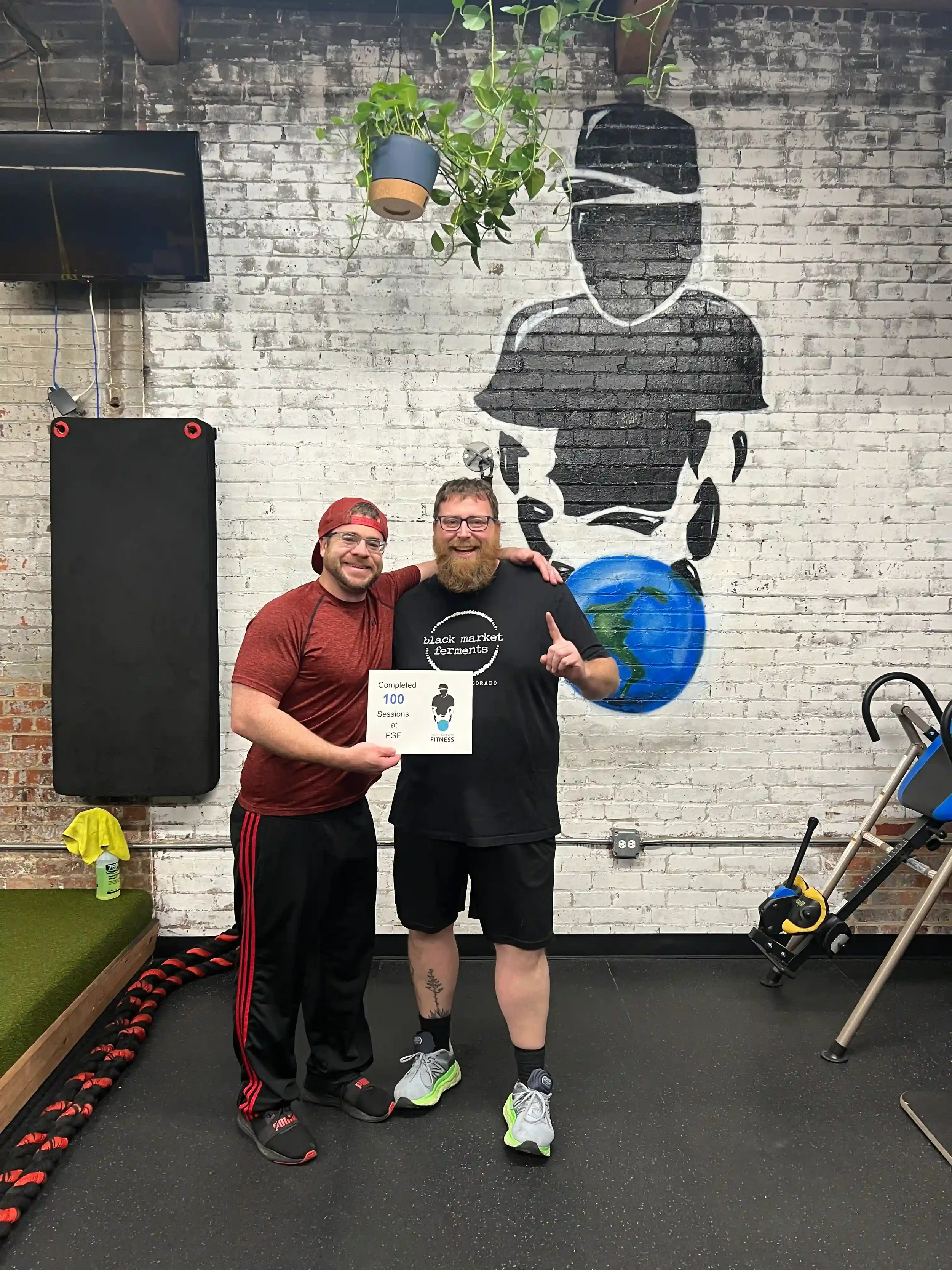 Fight Gravity Fitness client celebrating completion of 100 personal training sessions with trainer Nick Butler in the Denver fitness studio..webp
