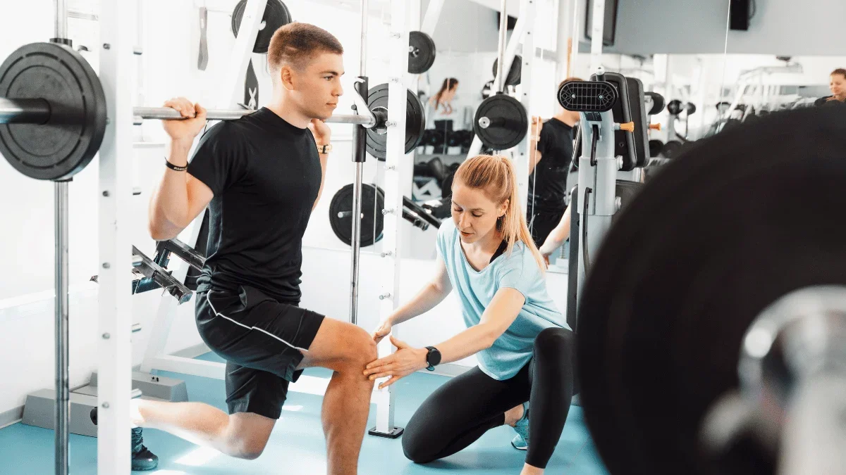 Personal trainer coaching a client through a strength training exercise to improve metabolic health and functional fitness.