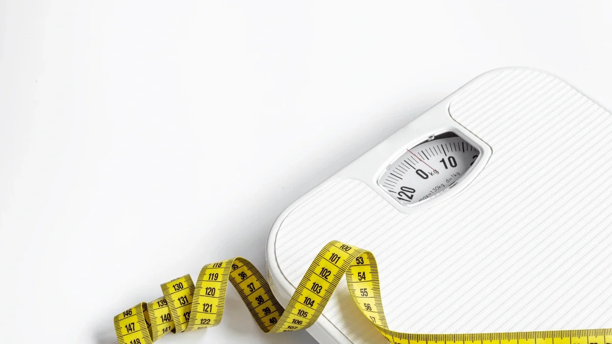 Bathroom scale and yellow measuring tape representing weight loss, body measurements, and progress tracking.