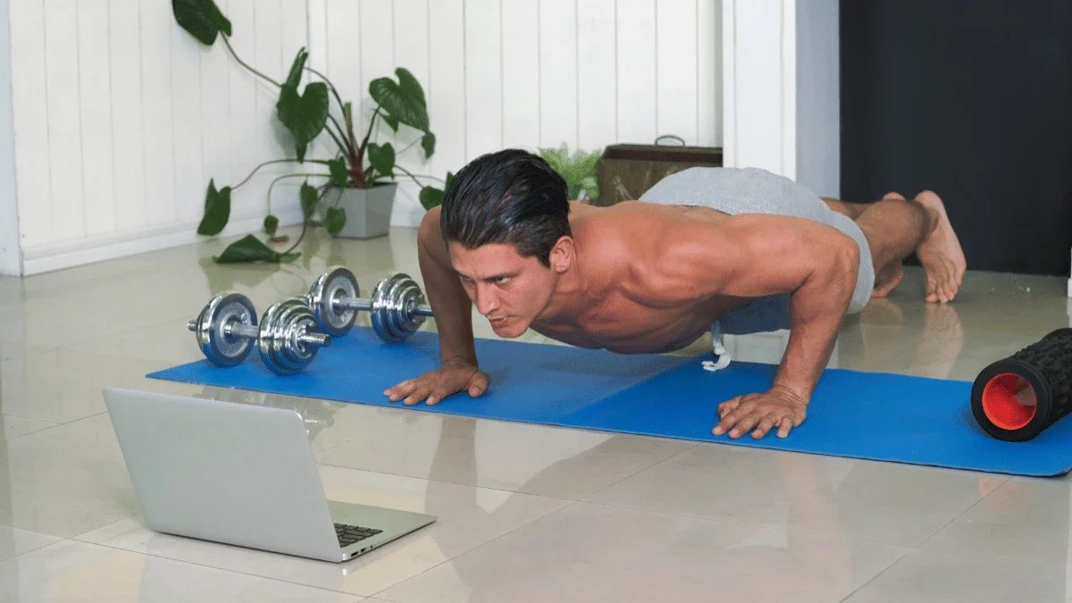 Man doing push ups at home while following a workout on laptop during lunch break
