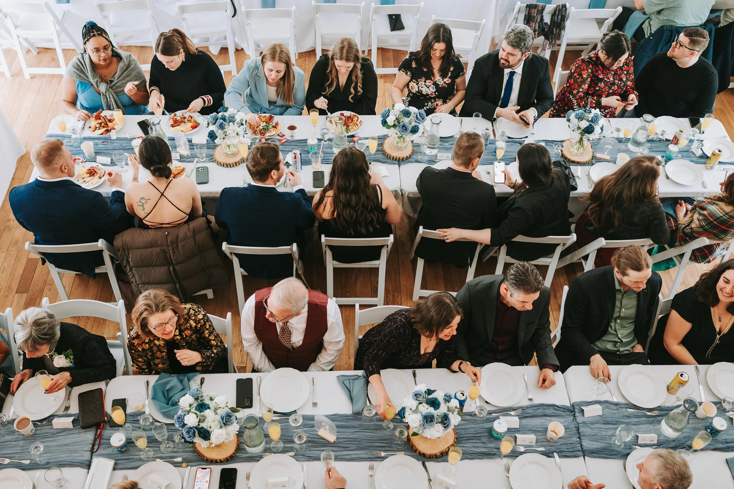 Overhead view of a multi-table banquet with guests dining and socializing at a formal event, decorated with blue and white floral centerpieces and table settings.