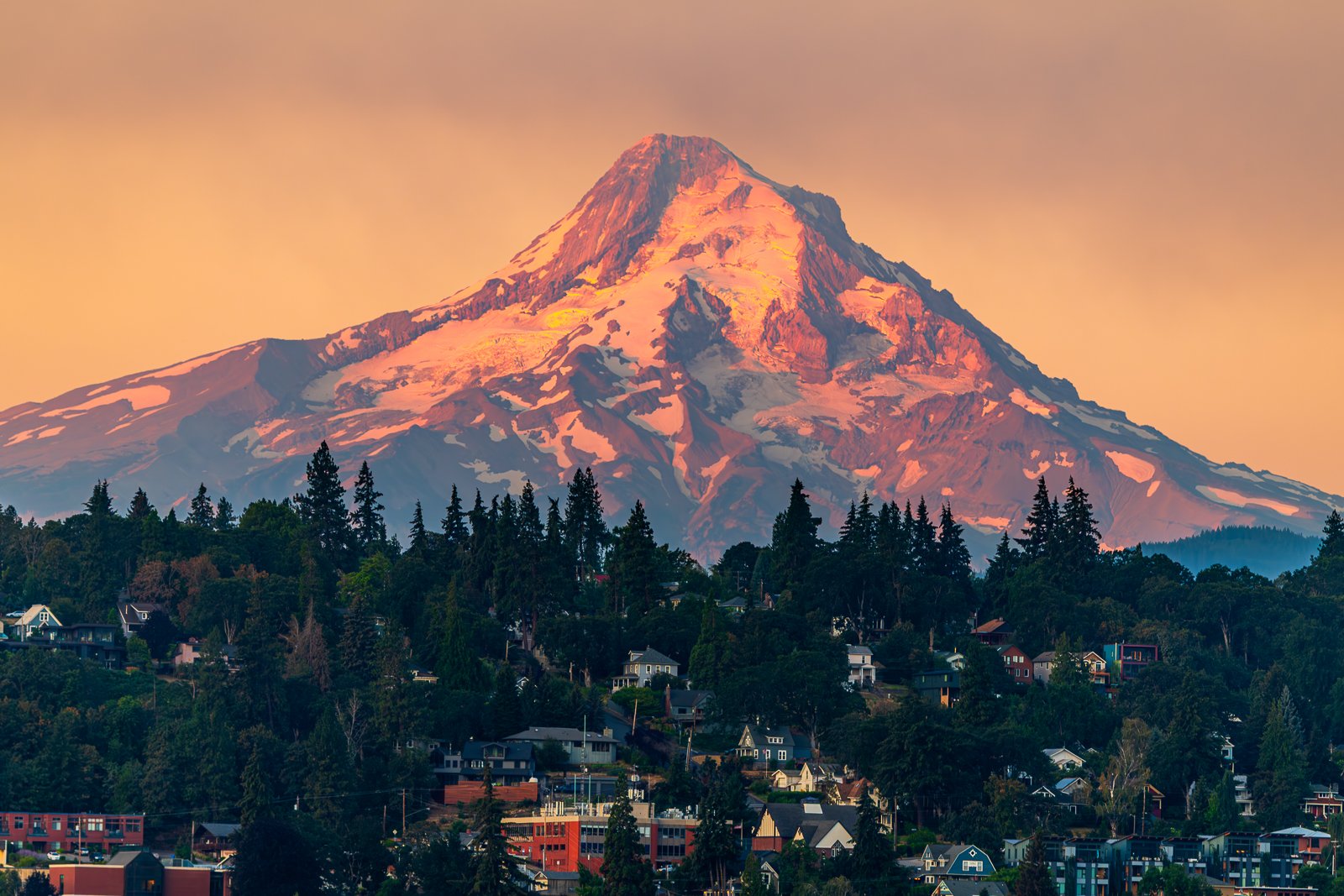 Mount Hood glows in warm evening light above Hood River, Oregon, with the town nestled below. Fine art landscape photography of the Pacific Northwest.