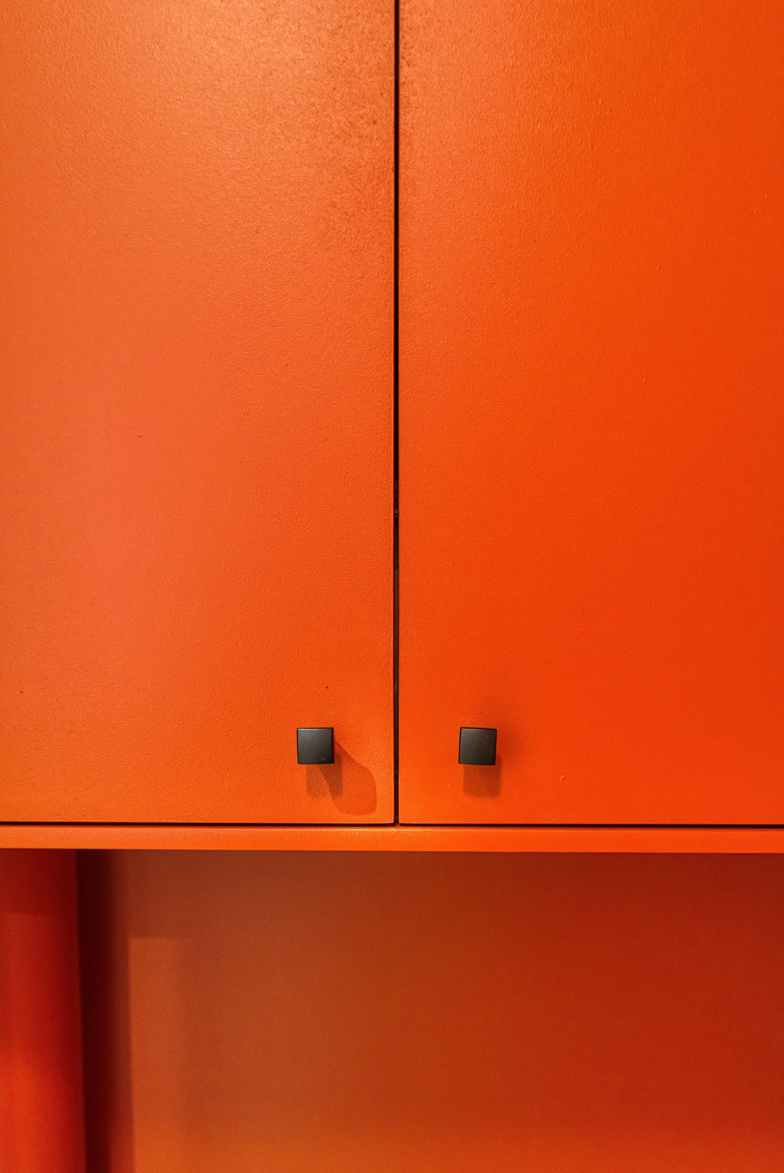 Murs et meuble sur mesure reprennent le même terracotta orange que le meuble bas de la bibliothèque, pour un fil conducteur entre les pièces