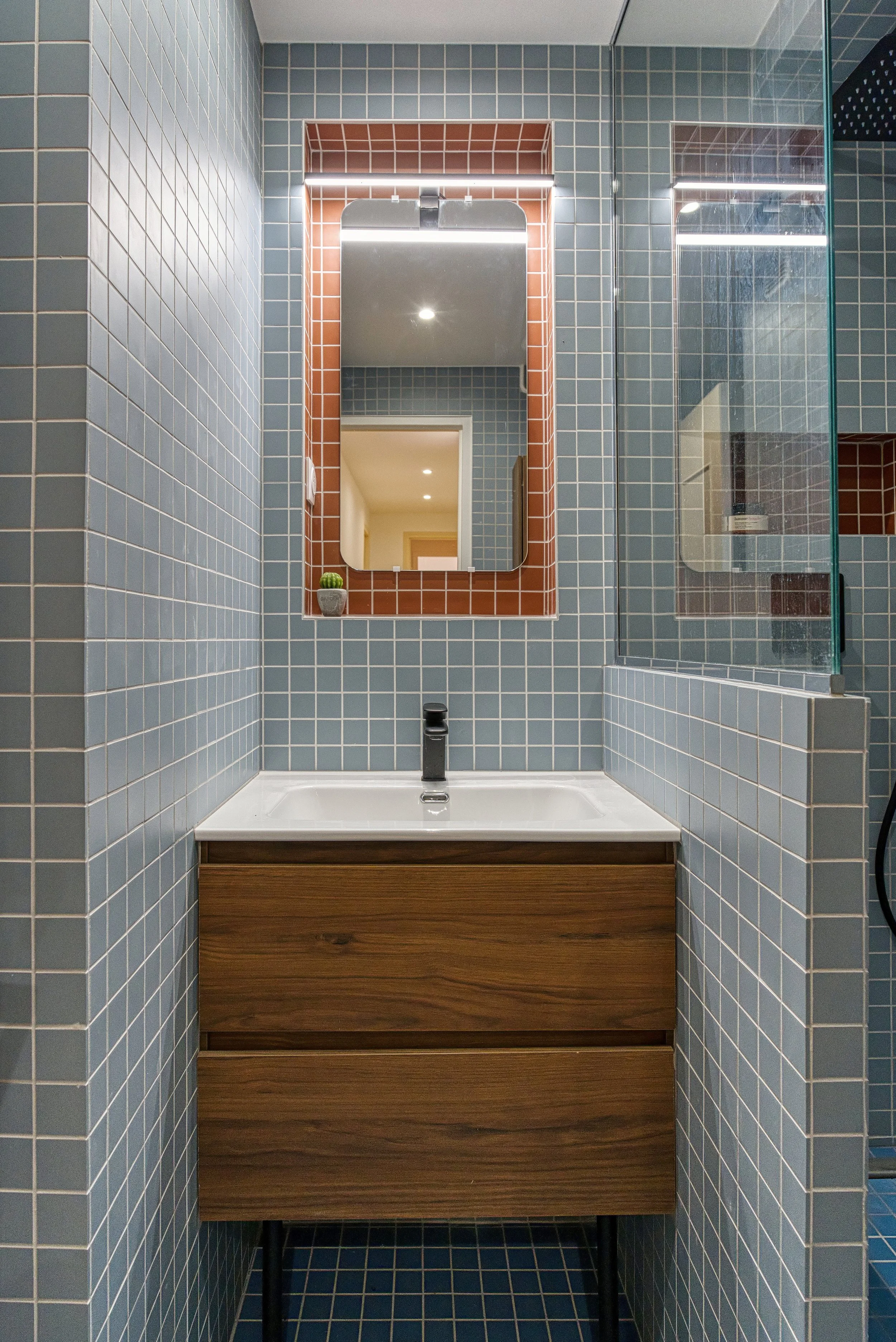Mosaïque bleu pâle et rouge Winckelmans se répondent au sol comme aux murs, jusque dans la niche du miroir