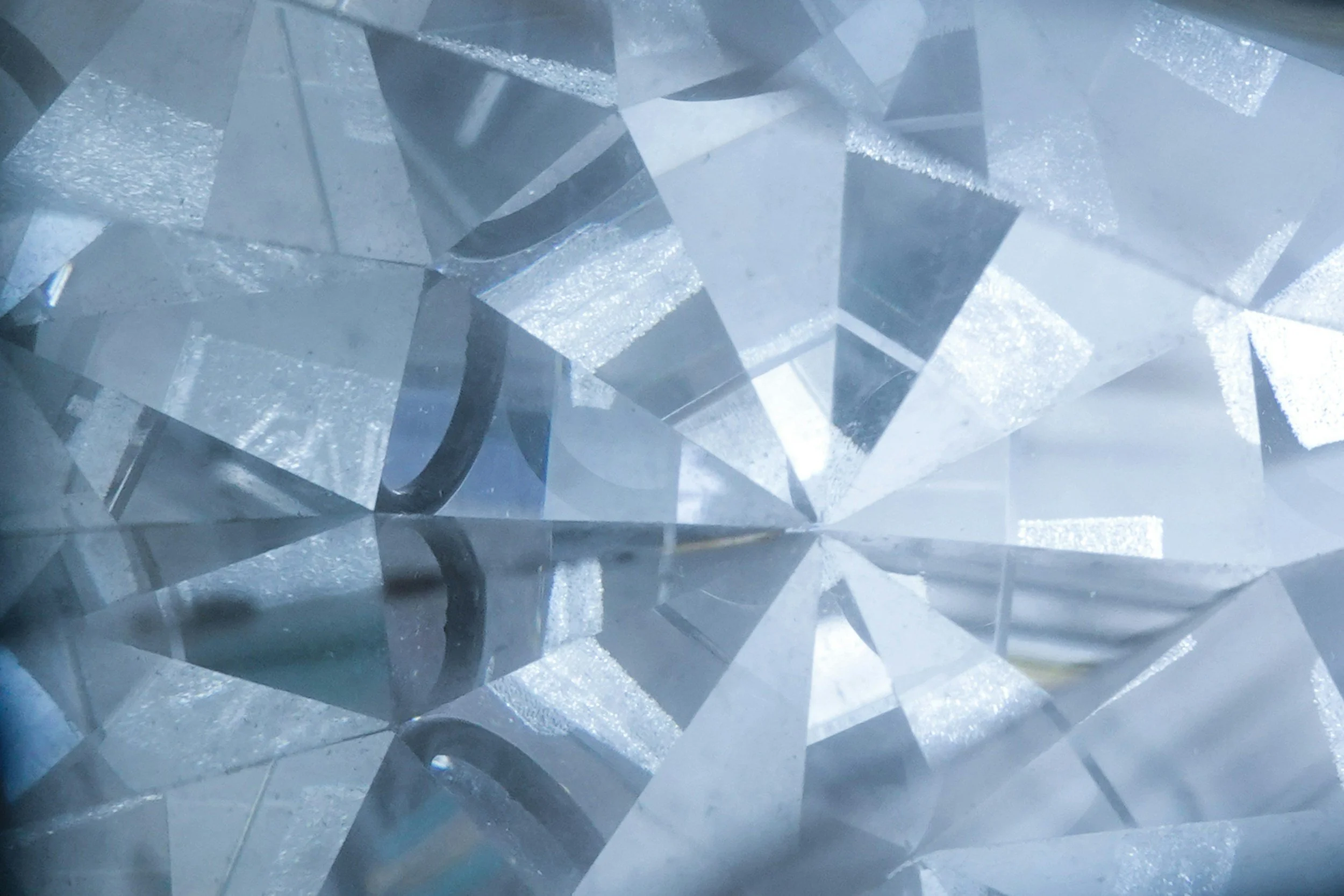 Close-up of faceted, transparent crystal or glass reflecting light with multiple reflective surfaces.