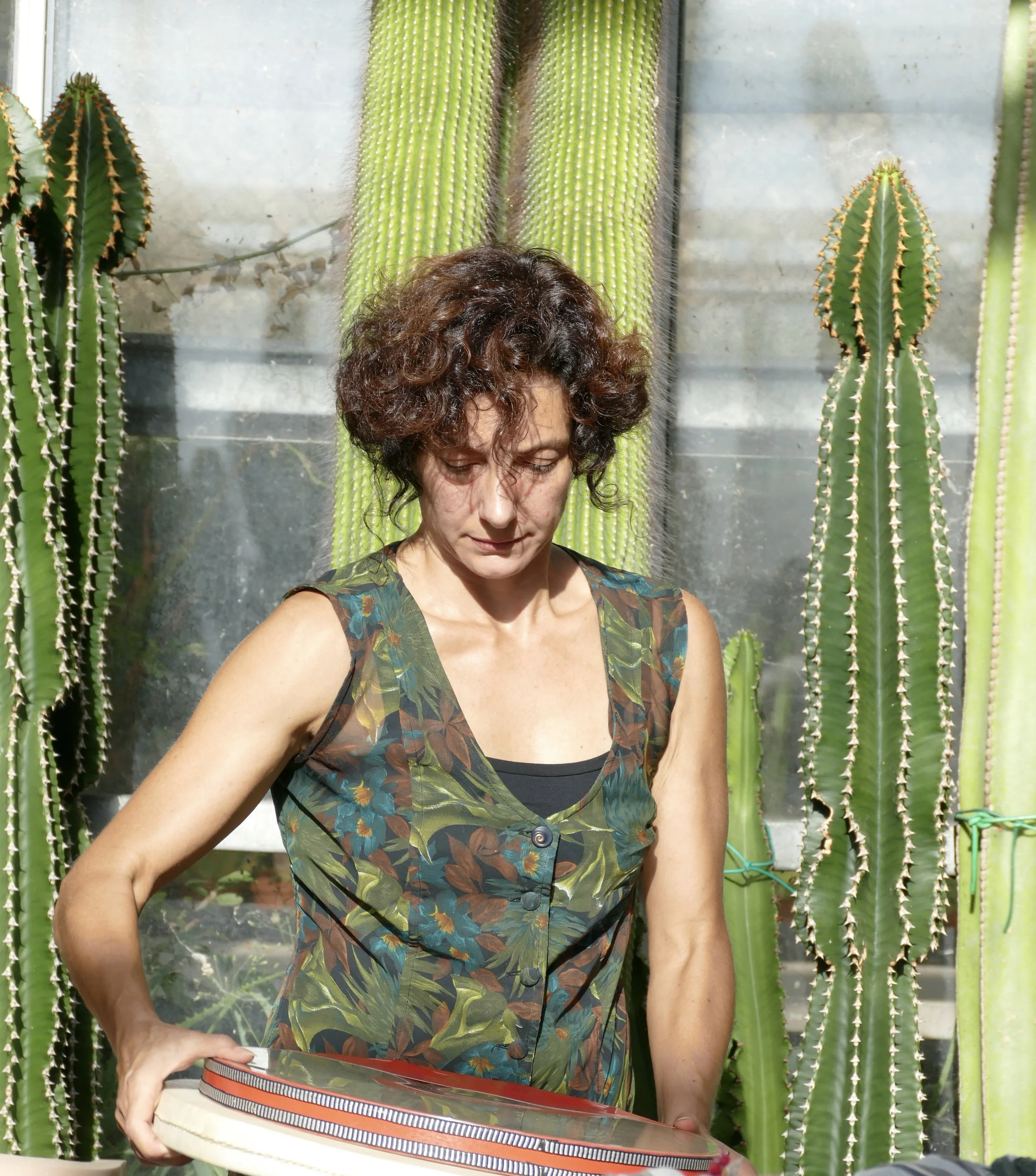 Two women with long dark hair sit at a table with crystals, a small potted cactus, and other objects, smiling at the camera.