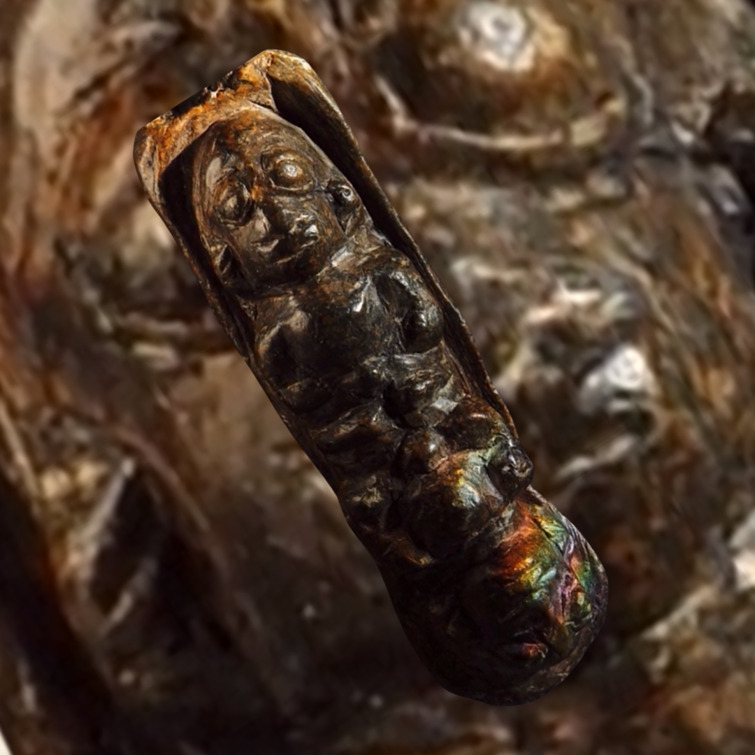 A carved wooden artifact resembling a human face and upper body, with a rounded shape and detailed features, situated against a blurred natural background.