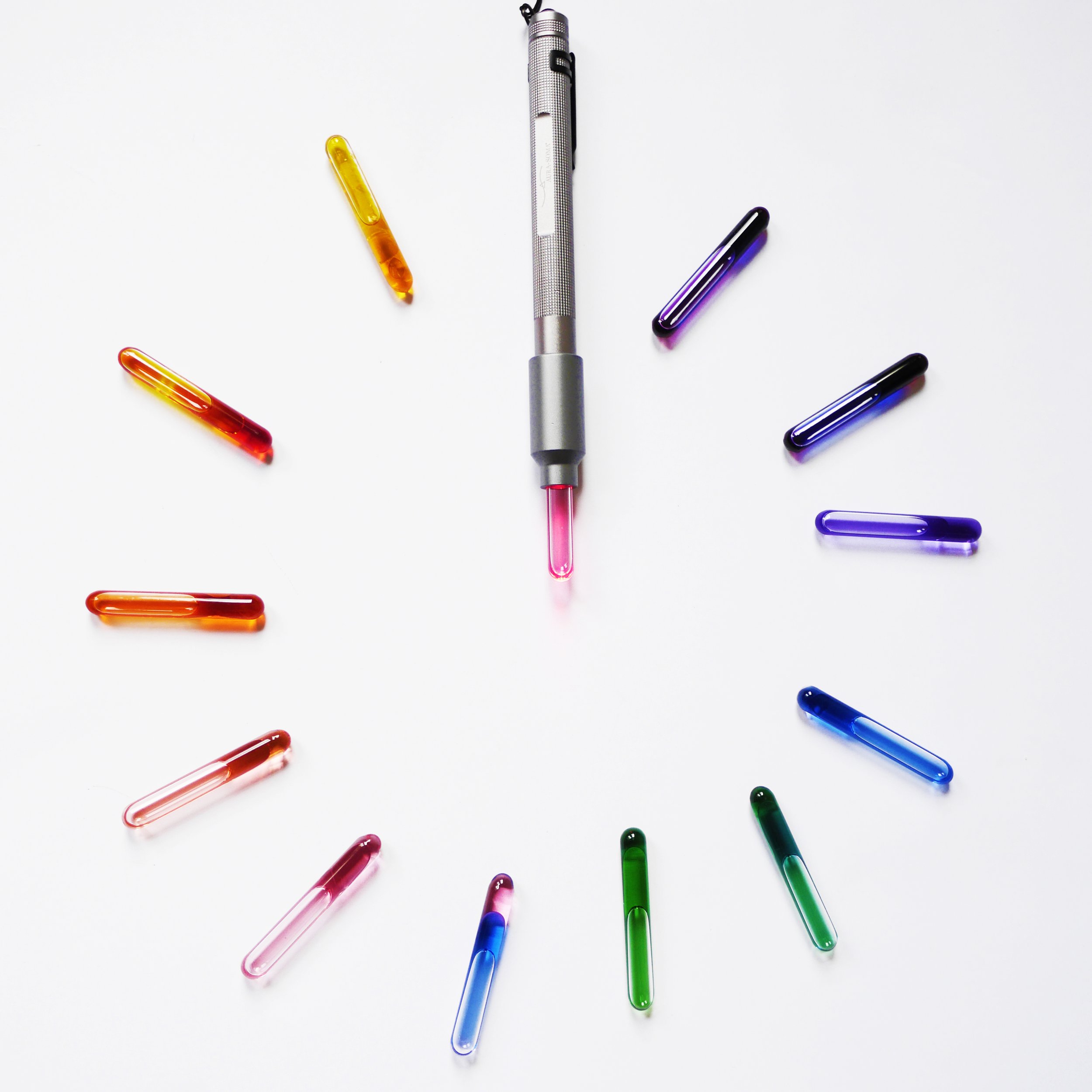 A pen with a pink glowing tip in the center, surrounded by colorful glass clips arranged in a clock-like pattern on a white surface.