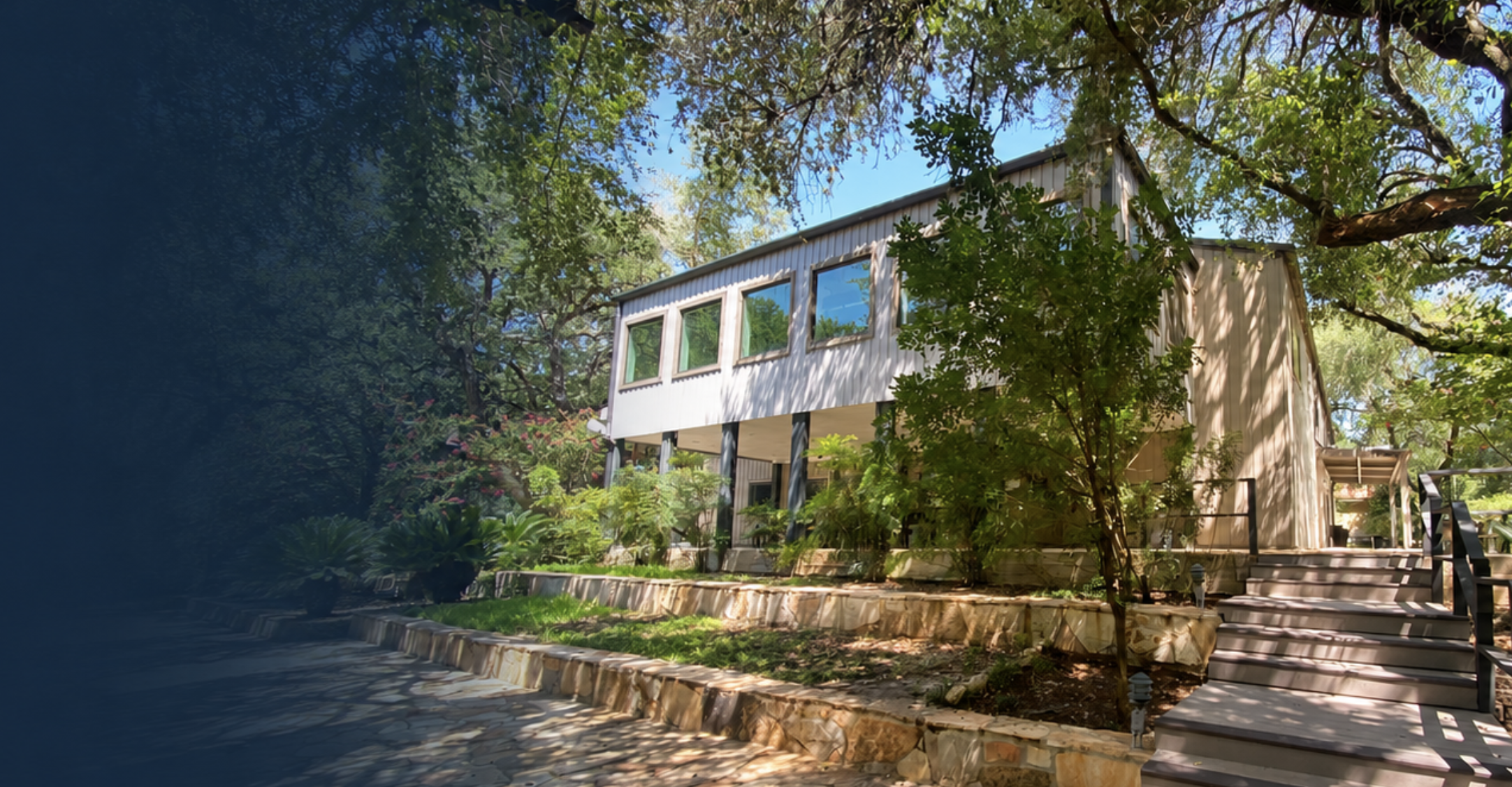 Modern commercial building surrounded by lush trees and landscaped stone terraces