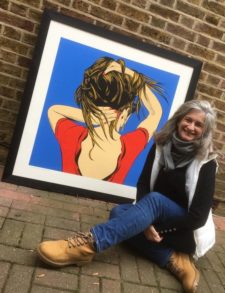 A photo of Deborah Azzopardi sitting on the ground in front of one of her artworks