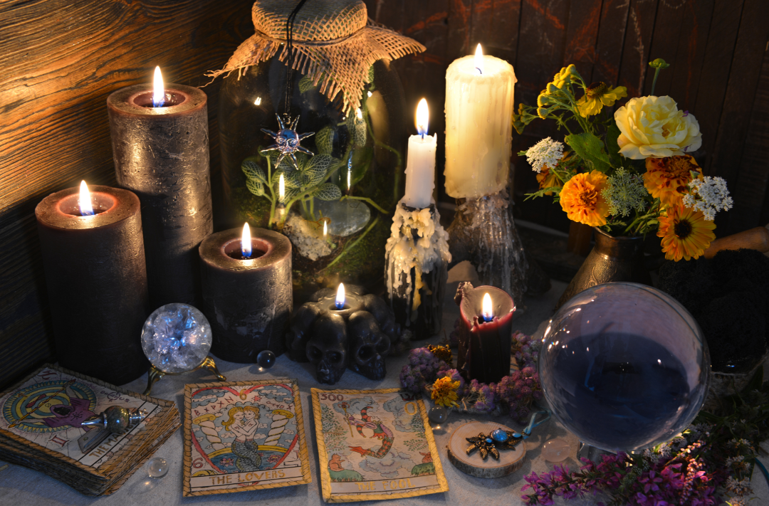 lit candles, crystals and tarot cards on a table with flowers and herbs