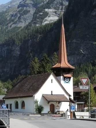 A small church with a brown tall pointed spire top