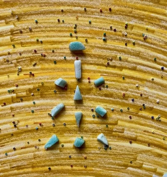Blue crystals in a grid formation over different shades of yellow and colorful tiny beads