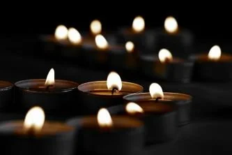 a cluster of lit votive candles in the dark