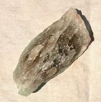 A raw piece of Aquamarine crystal with varying tones of blue, grey and green as well as white