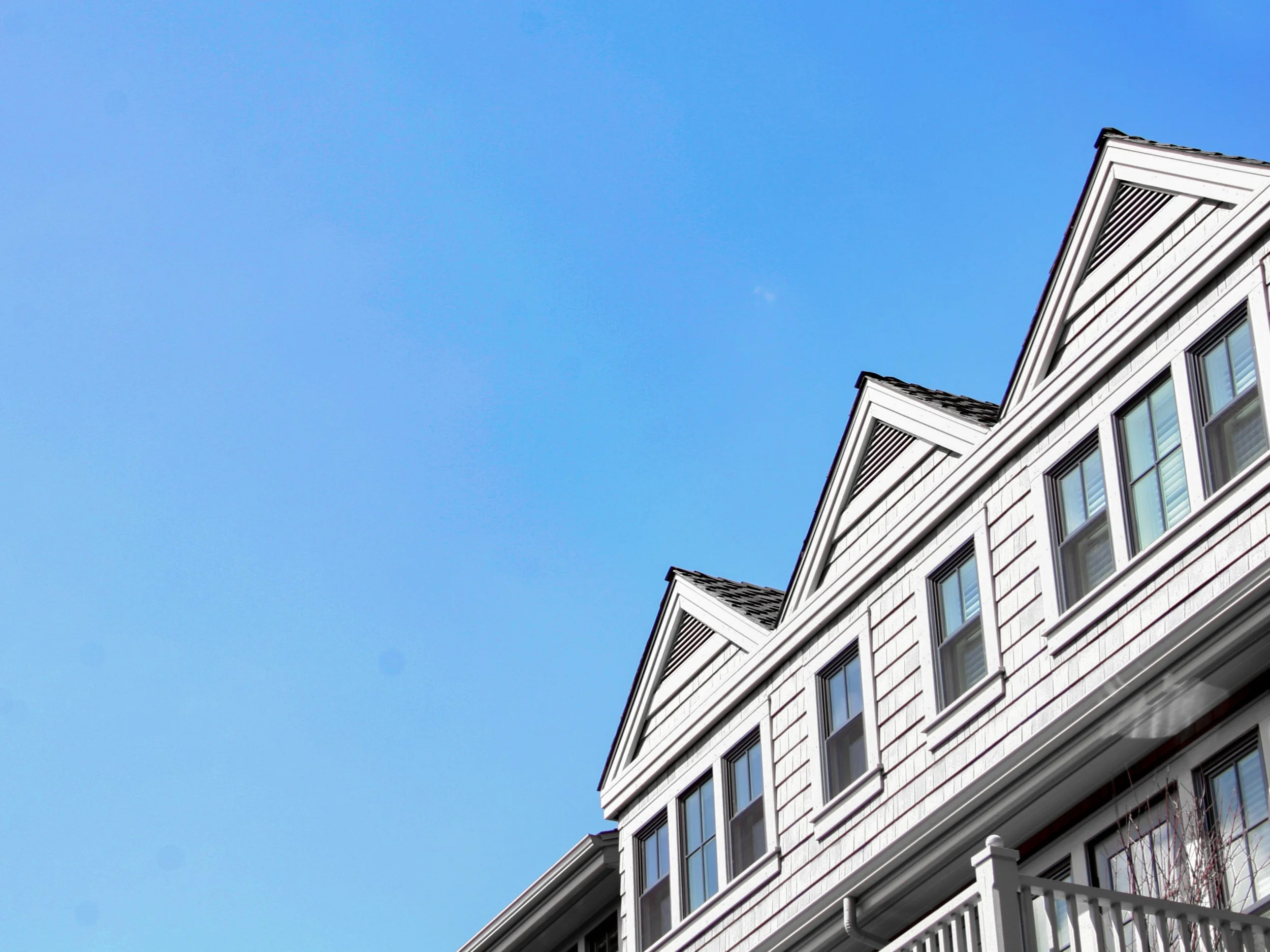 Bottom view of townhomes with a new siding and  beautiful blue sky in the background.