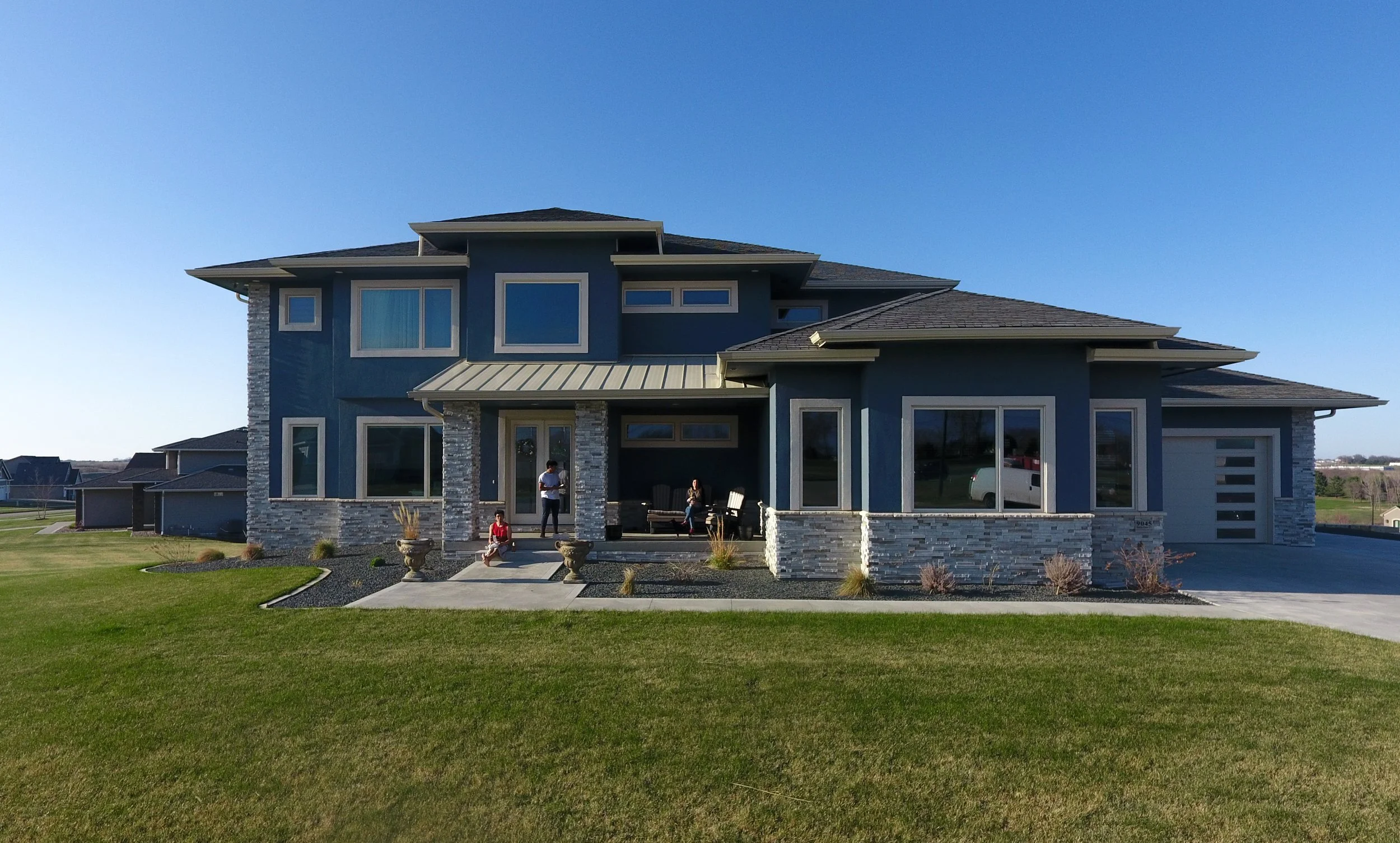 Front view of a big blue home in a Norwalk neighborhood displaying new siding, roofing, gutters, and windows.