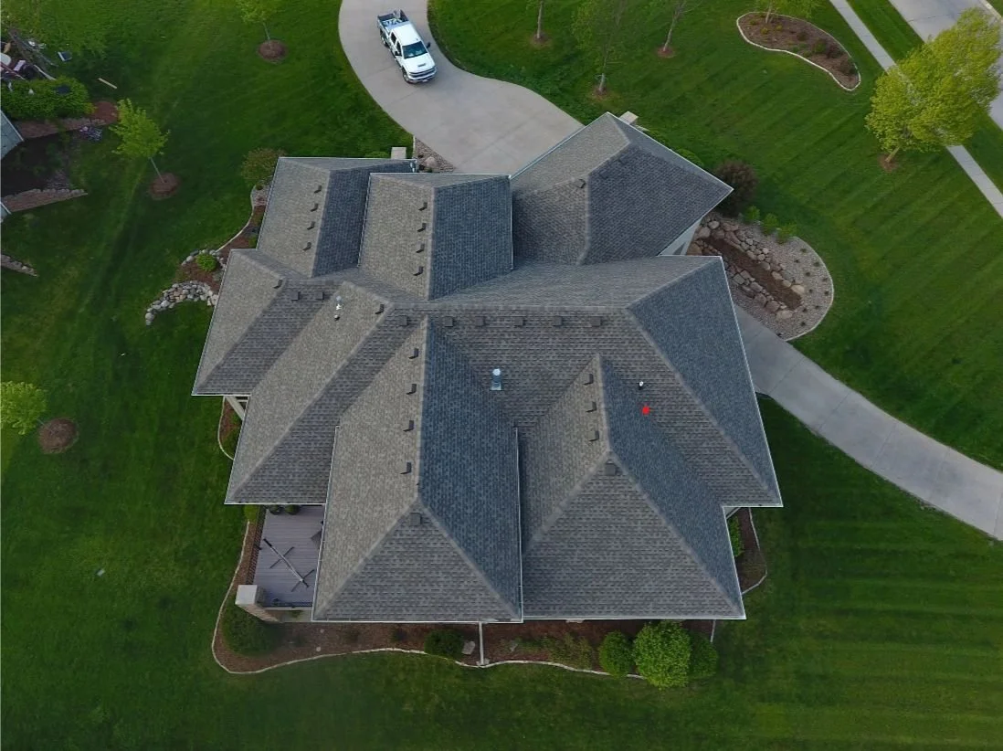 Drone picture of house showing roof, vents, and car.