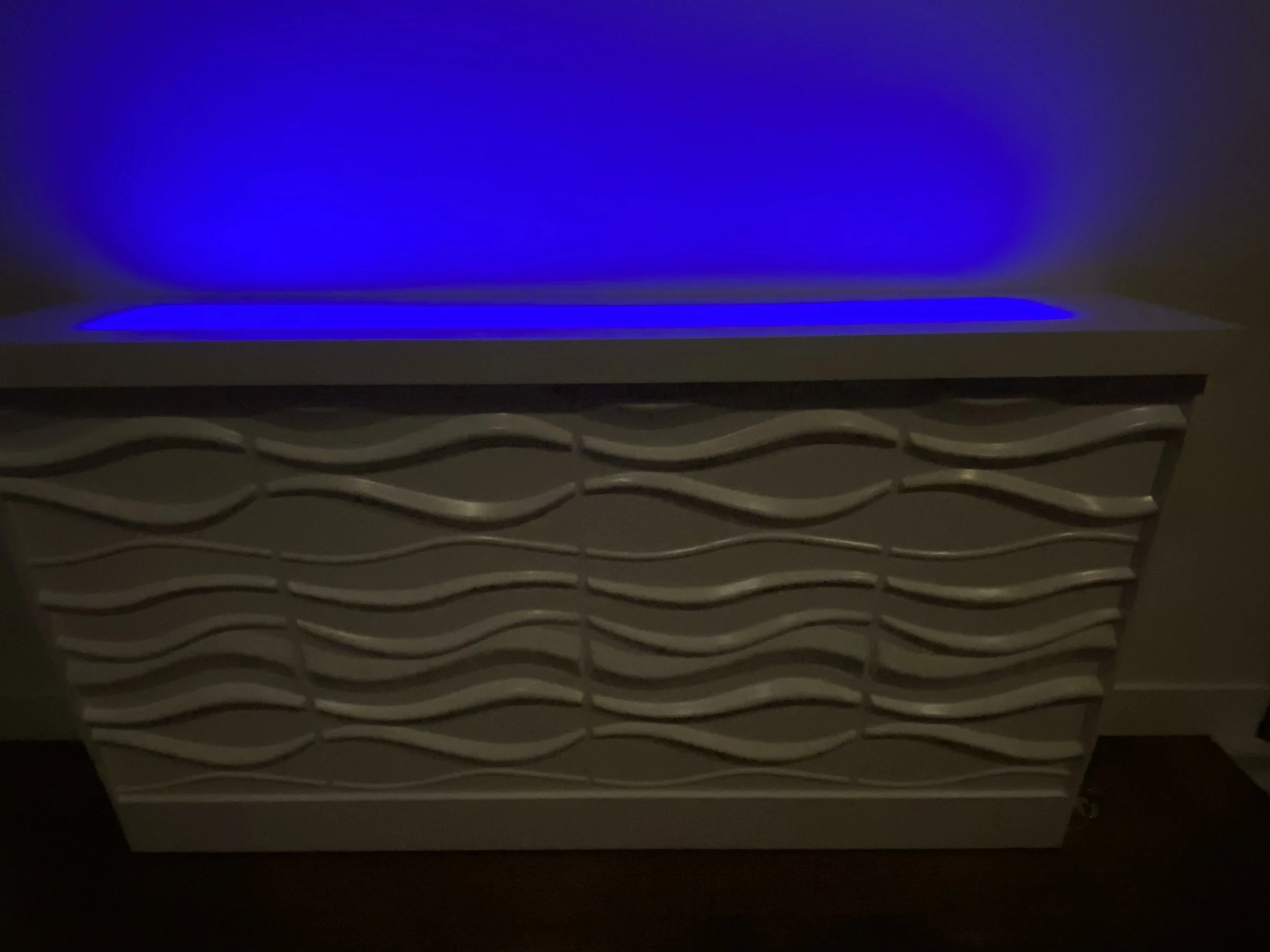 Indoor rising TV cabinet with wave theme and multi colored LED to highlight sculpture