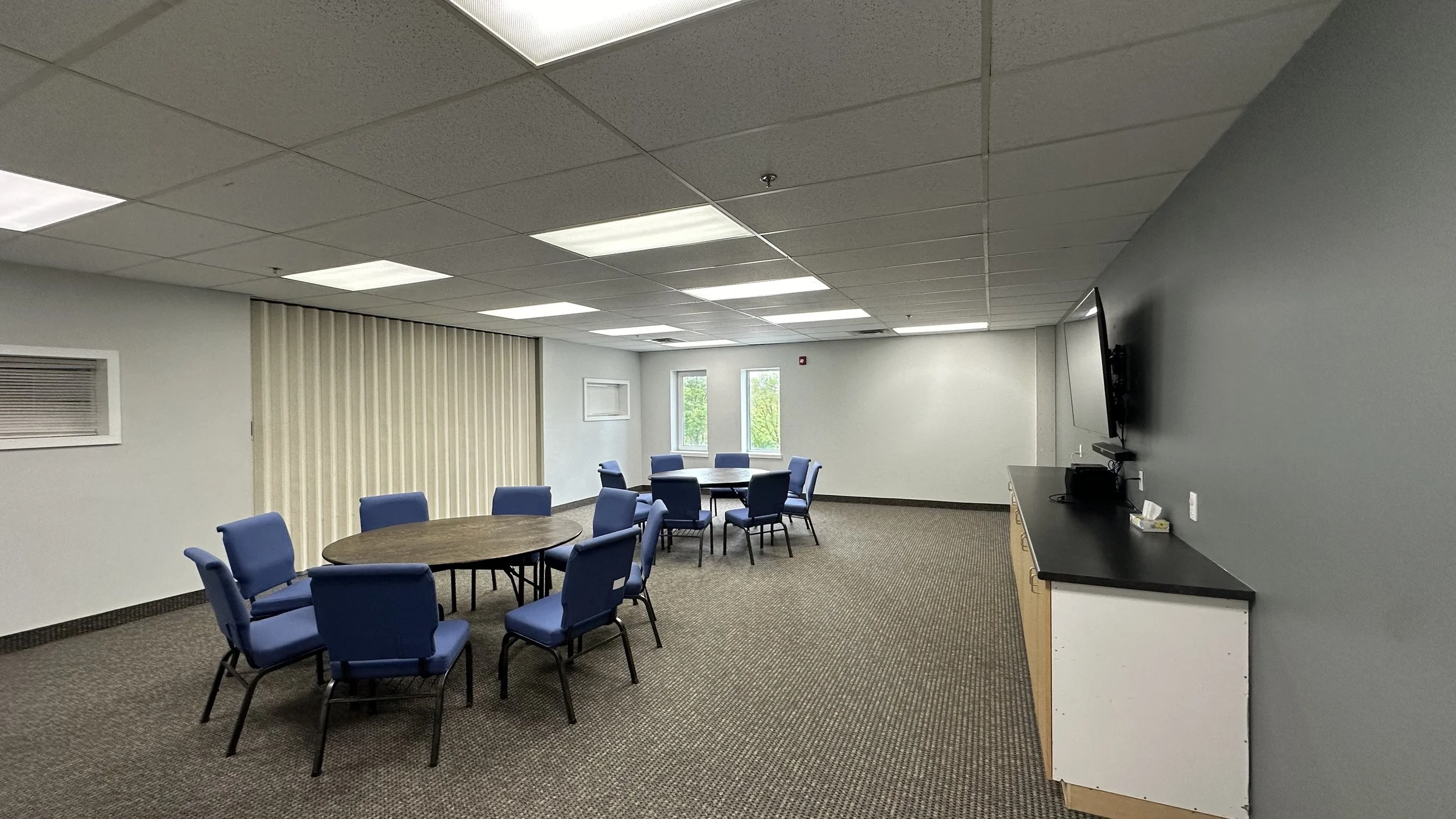An open white room space, two narrow rectangle windows, with TV monitor mounted on the wall over a counter.