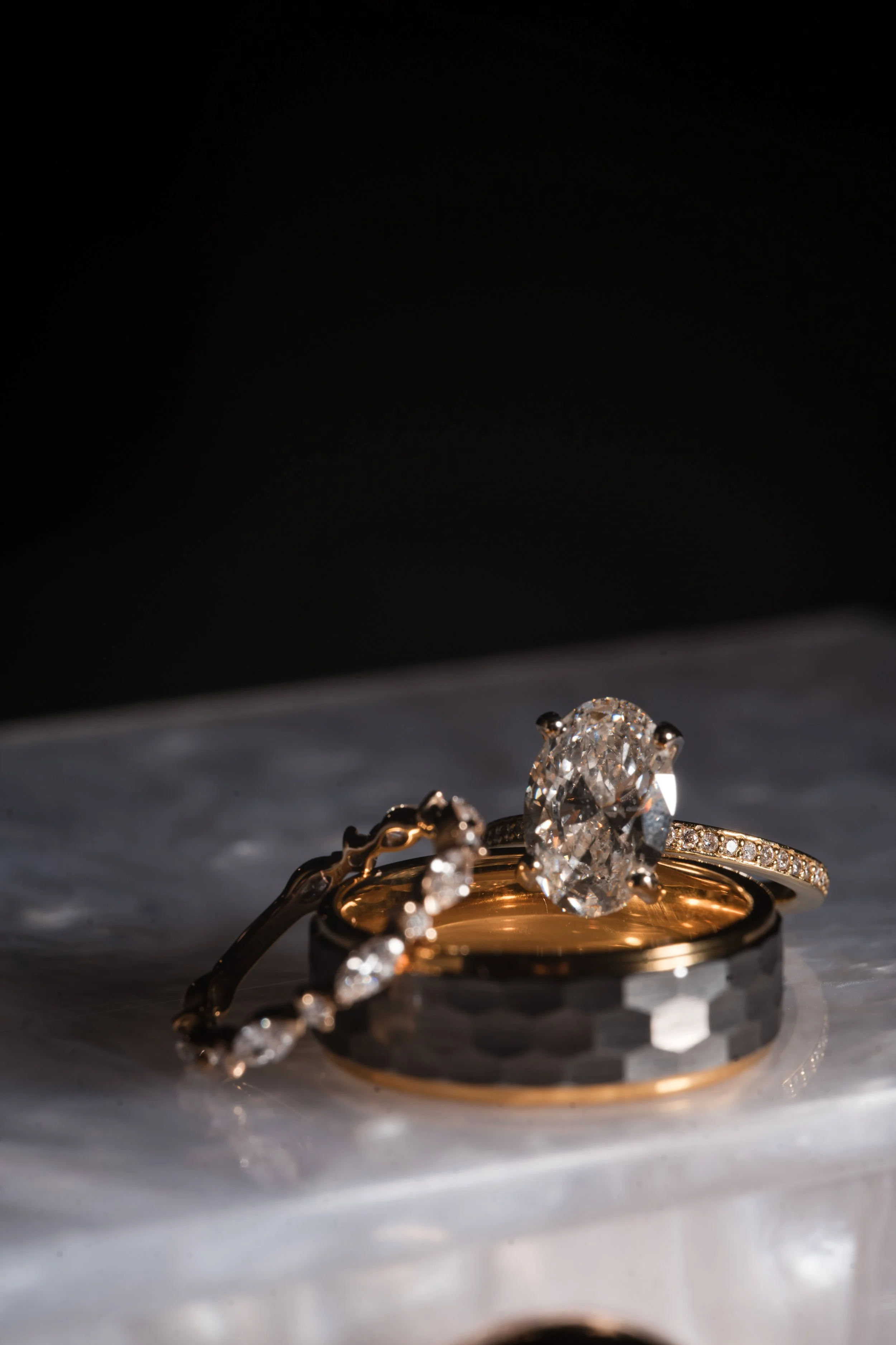Three rings with diamonds resting on a marble surface.