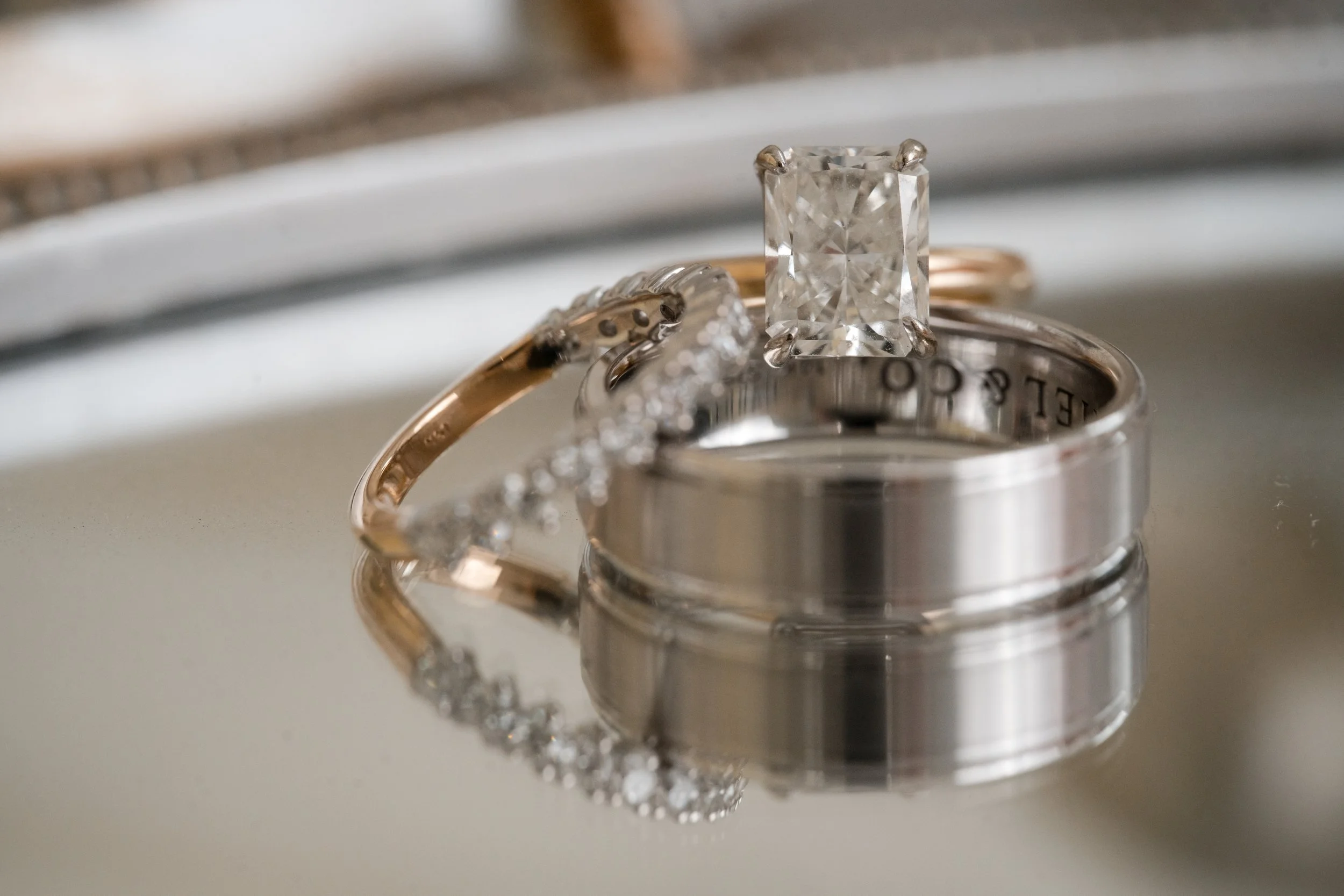 Close-up of three wedding or engagement rings with a reflective surface.