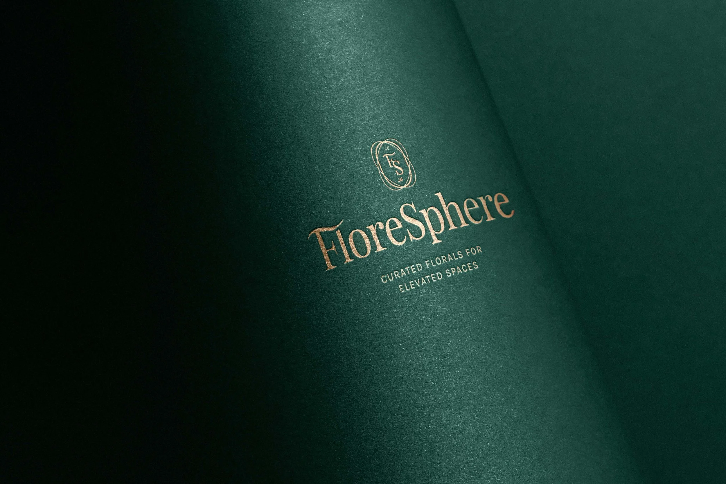 Close-up of a dark green box with gold text that reads 'FLOREsPHERE' and 'Curated Florals for Elevated Spaces'.