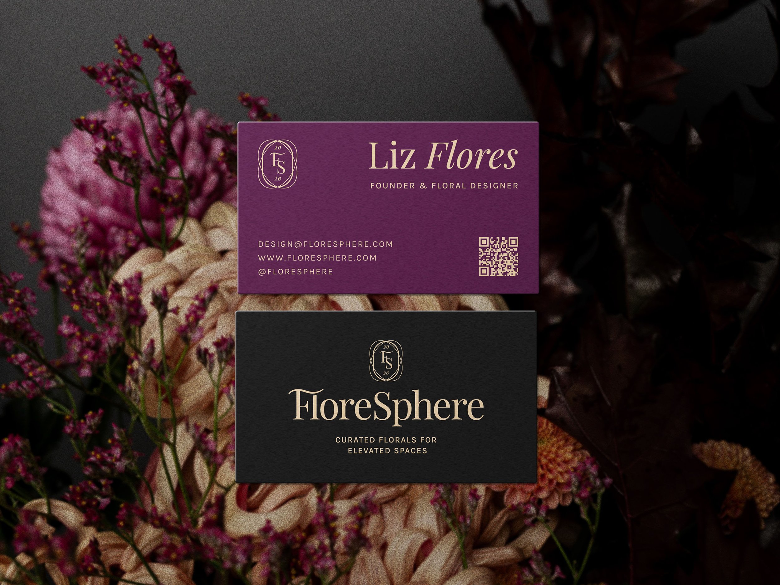 Two business cards placed on a bouquet of pink and burgundy flowers. One card is purple with Liz Flores' contact info, and the other is black with FloreSphere branding.