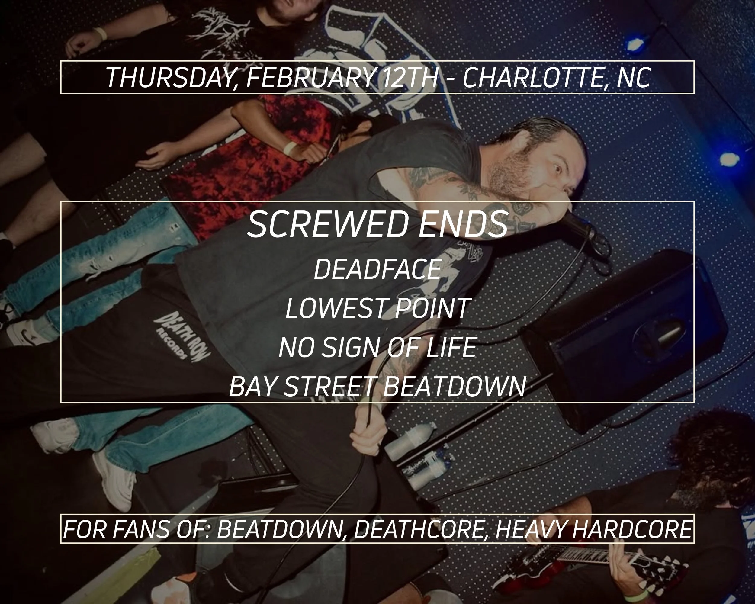 A performer singing into a microphone on stage at a concert with a person playing guitar nearby. There are other people in the background and the stage has dark lighting.