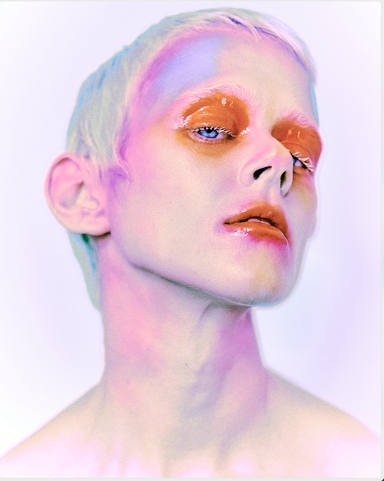 A close-up portrait of a person with pastel-colored makeup and hair, with an artistic, surreal effect.