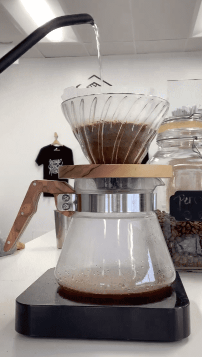 barista pouring water into pour over, one of the best coffee orders to try for beginners.