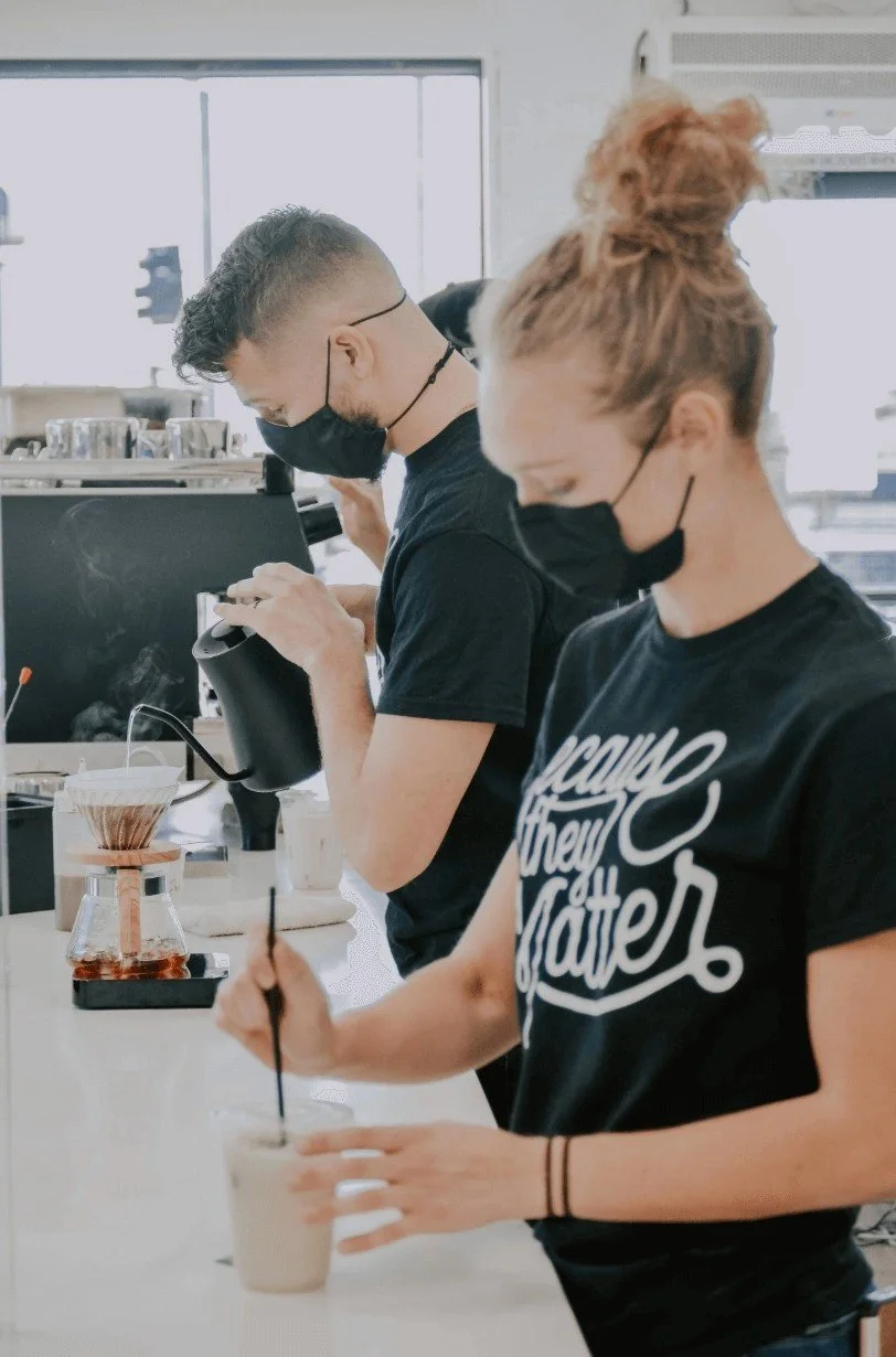 baristas with masks on making drinks during opening week