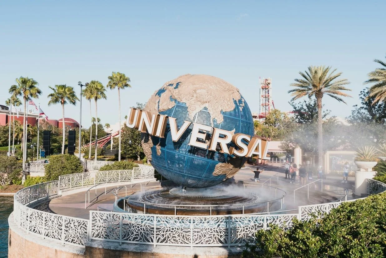 The entrance to Universal Studios with the Universal logo across the globe. Palm trees in the background.