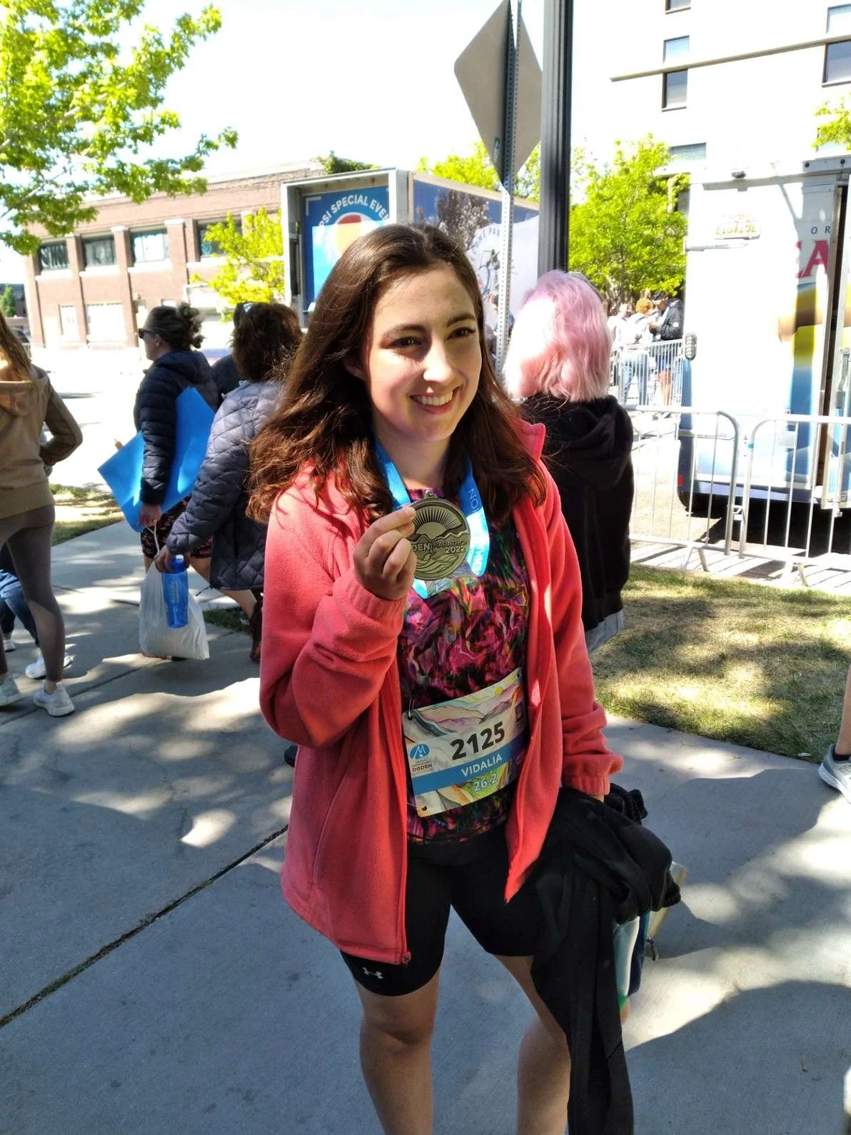 Runner holding up a race medal