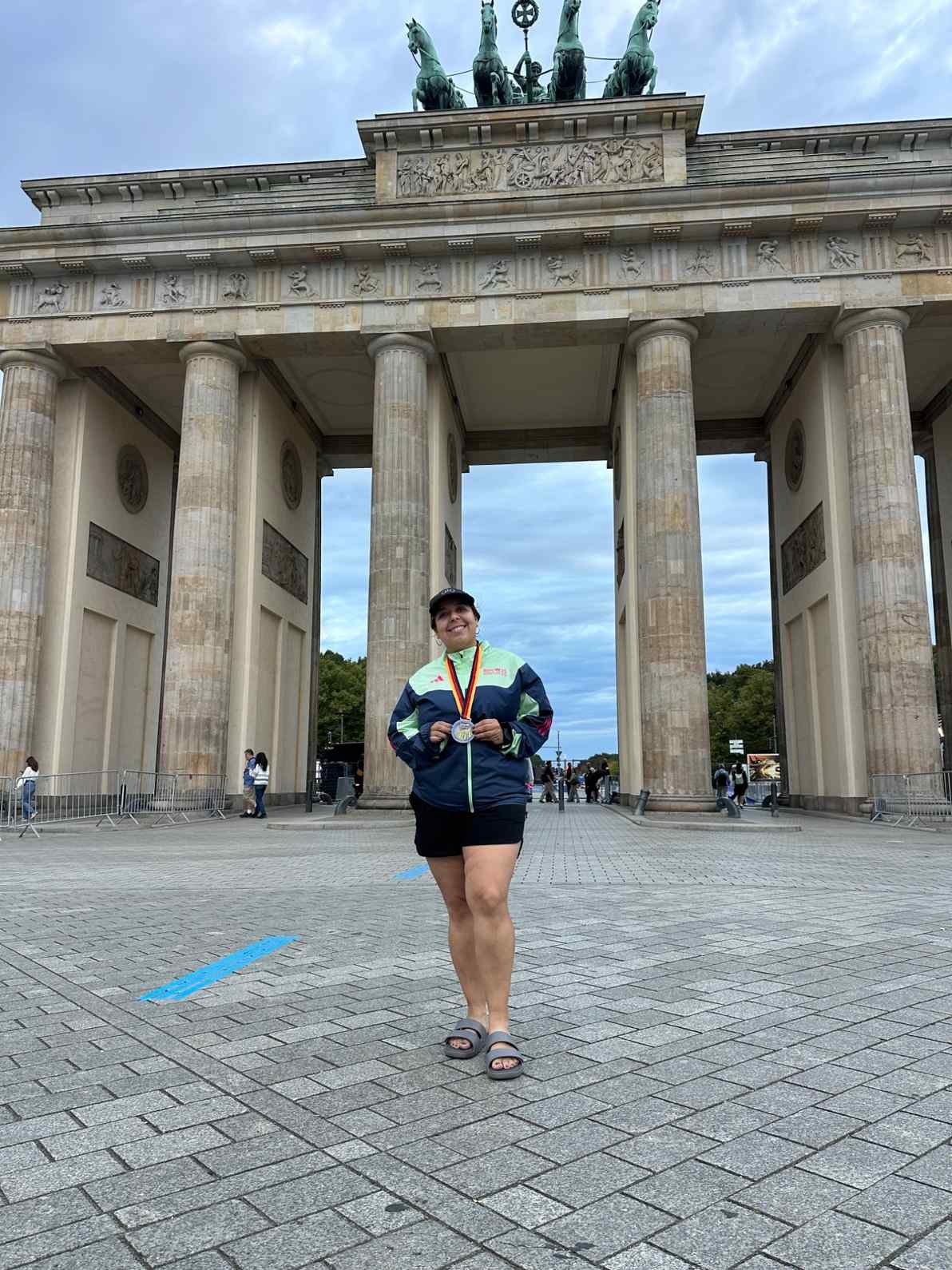 Woman holding a medal in front of the Brandenburg Gate in Berlin, Germany.