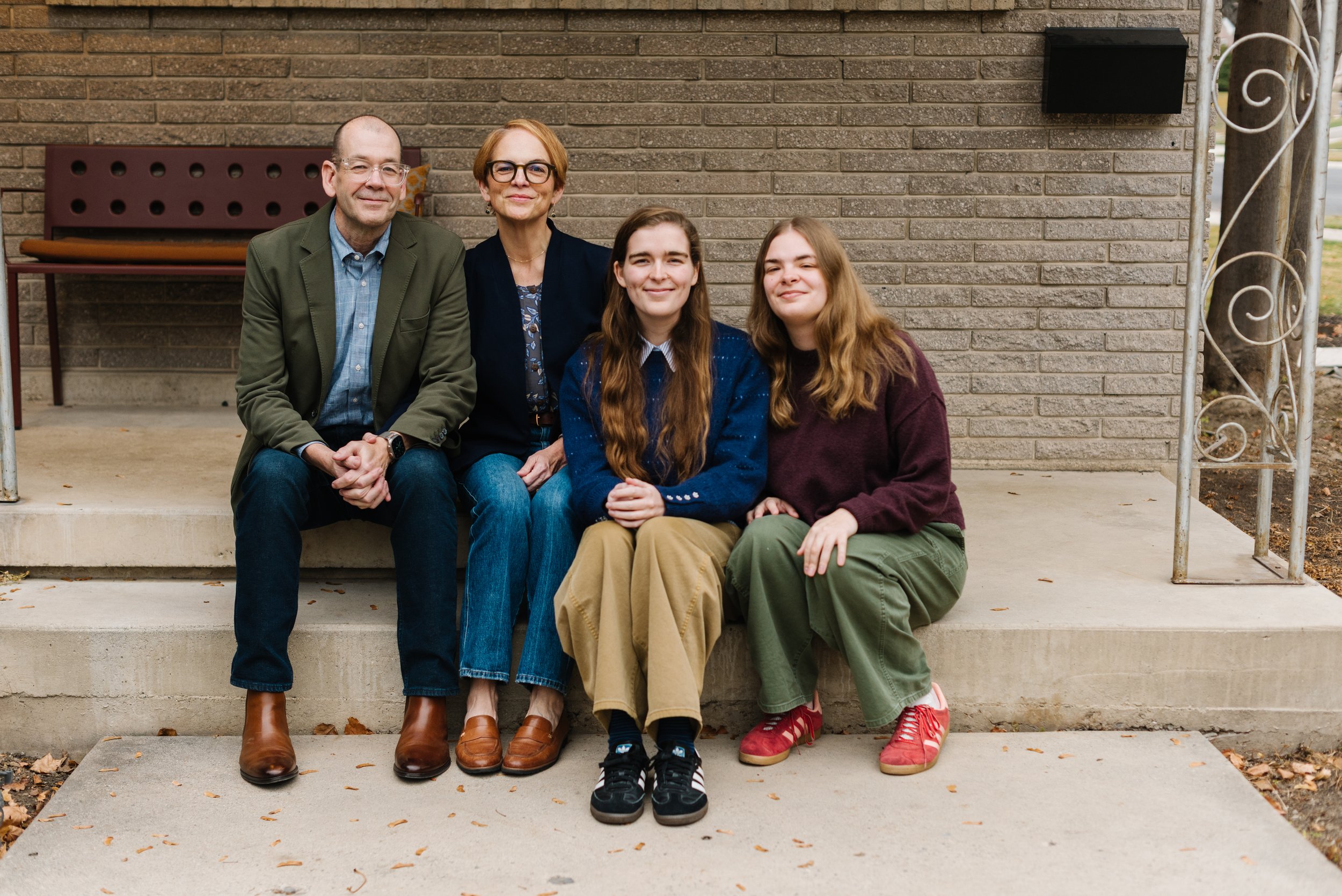 The Family sitting on concrete steps, smiling at the camera.