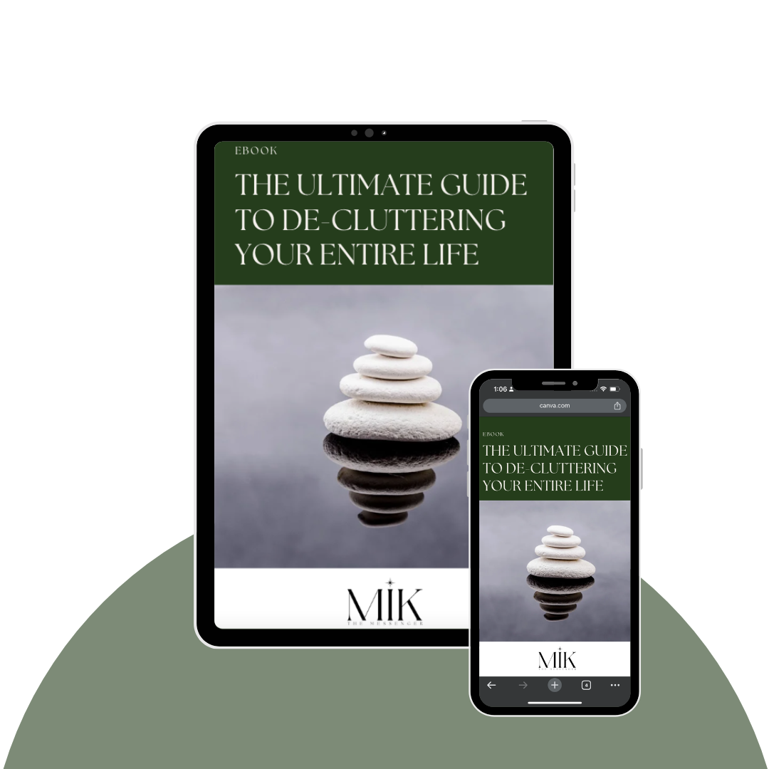 Cover of an e-book titled 'The Ultimate Guide to De-Cluttering Your Entire Life,' featuring a stack of four white stones reflected in water on a gray background, displayed on a tablet and a smartphone.