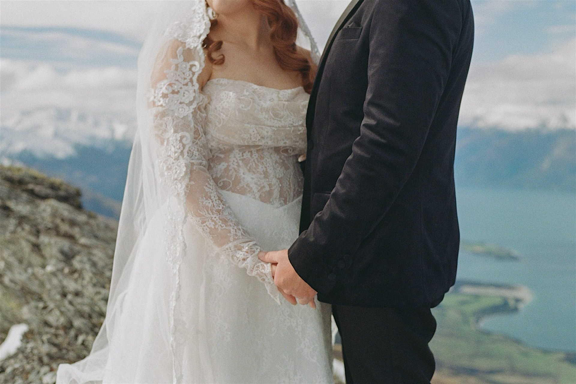  A close up photo of a married couple holding hands high on a snowy mountain in Wanaka taken on 35mm film 
