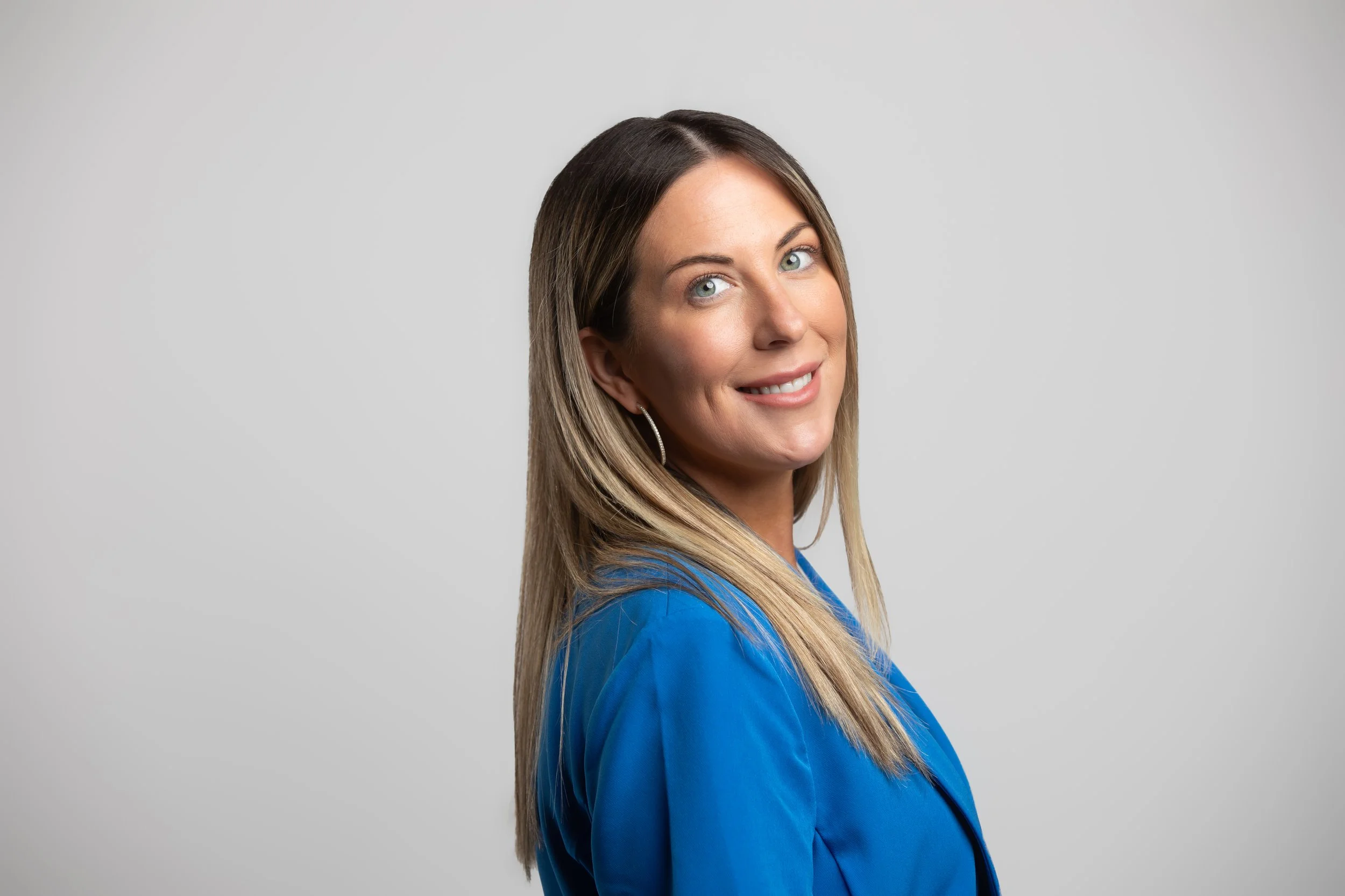 A modern building with wooden vertical siding and a large glass window, set against a mountainous landscape with dry grassy terrain and a cloudy sky.