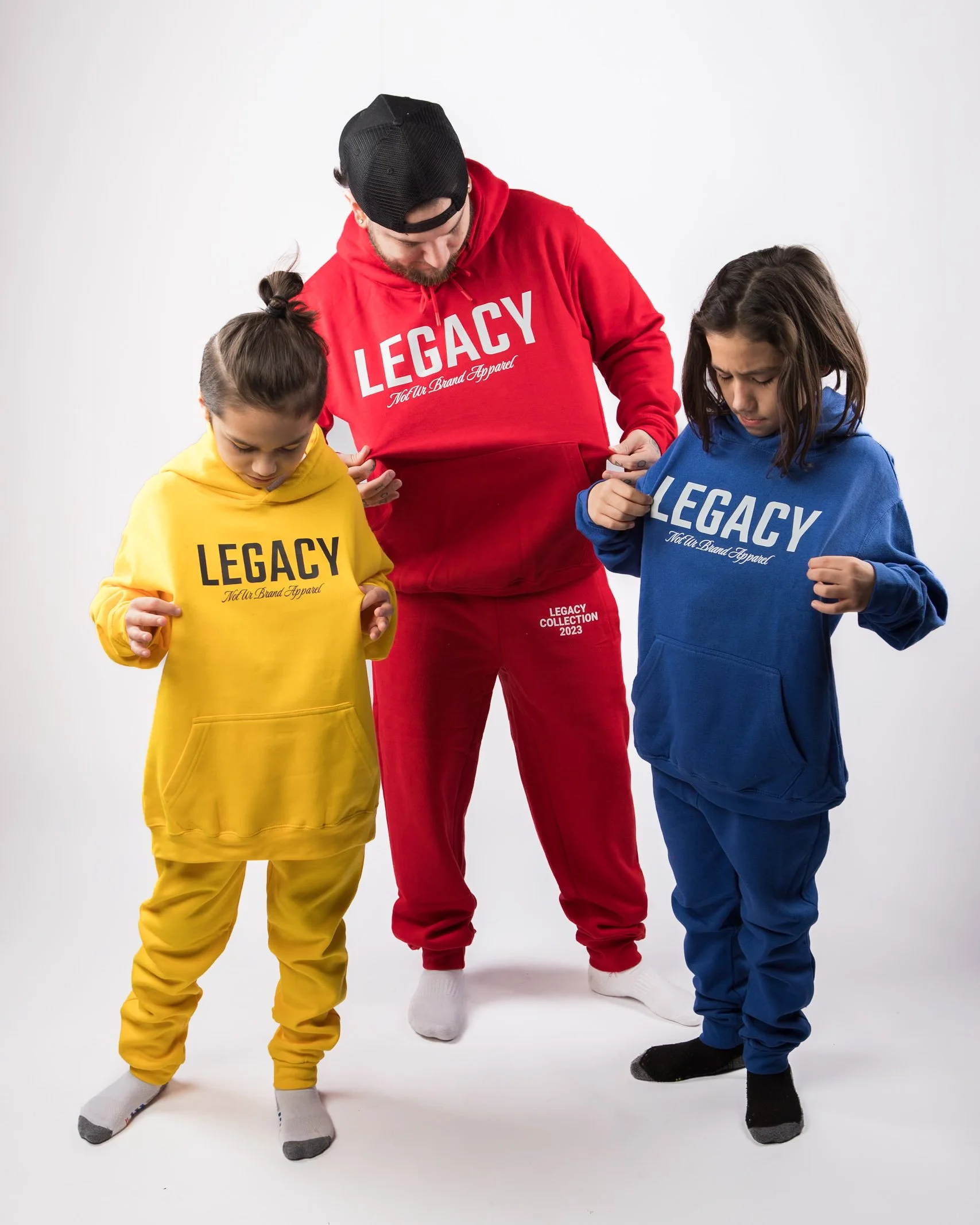 A man and two young girls wearing matching hoodies and sweatpants, all displaying the word 'LEGACY' on the front.