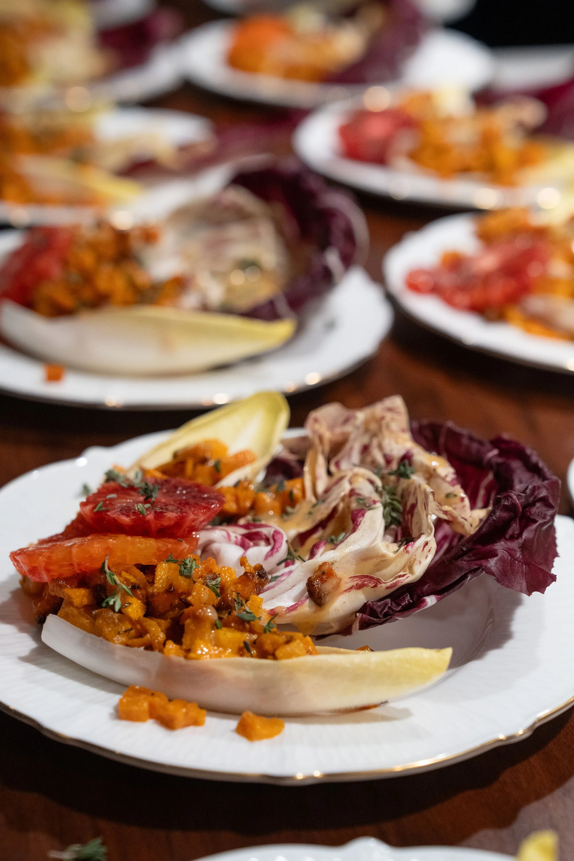 Close-up of a plate with assorted stuffed vegetables, including an eggplant, filled with a mixture of rice, vegetables, and herbs, garnished with chopped herbs. There is a lemon wedge on the plate.