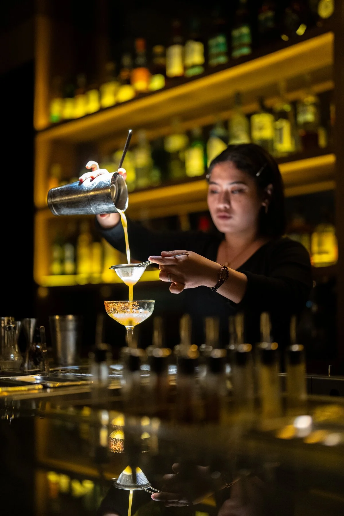 A White Rabbit bartender straining a cocktail into a coupe