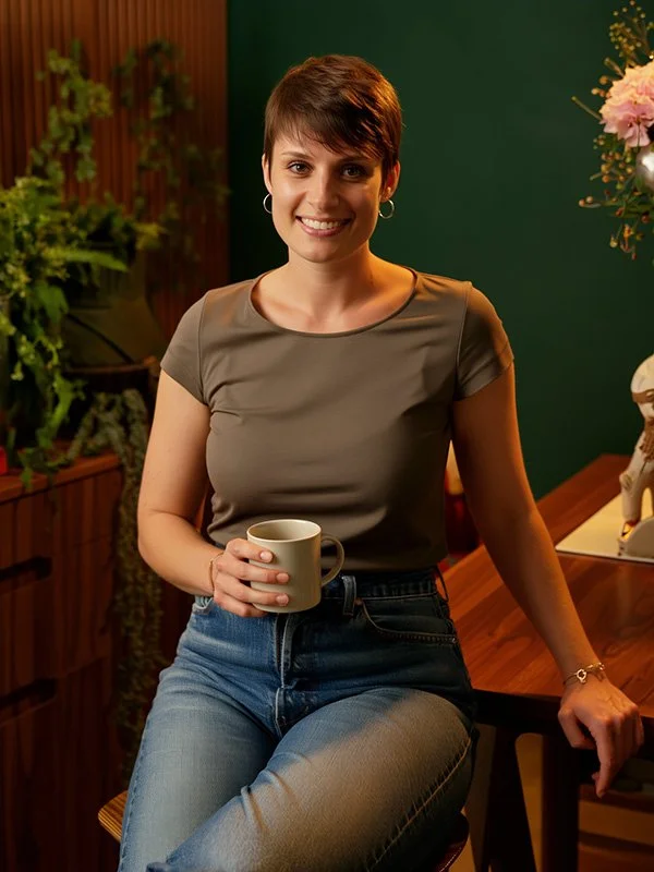 Portrait de Cécile Tellier, jeune femme souriante et dynamique posant dans un bureau aux couleurs vertes et bois