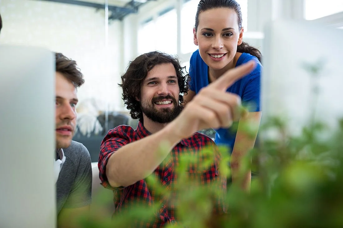 Equipe de 2 hommes et 1 femme au bureau qui visualisent un support finalisé à l'écran