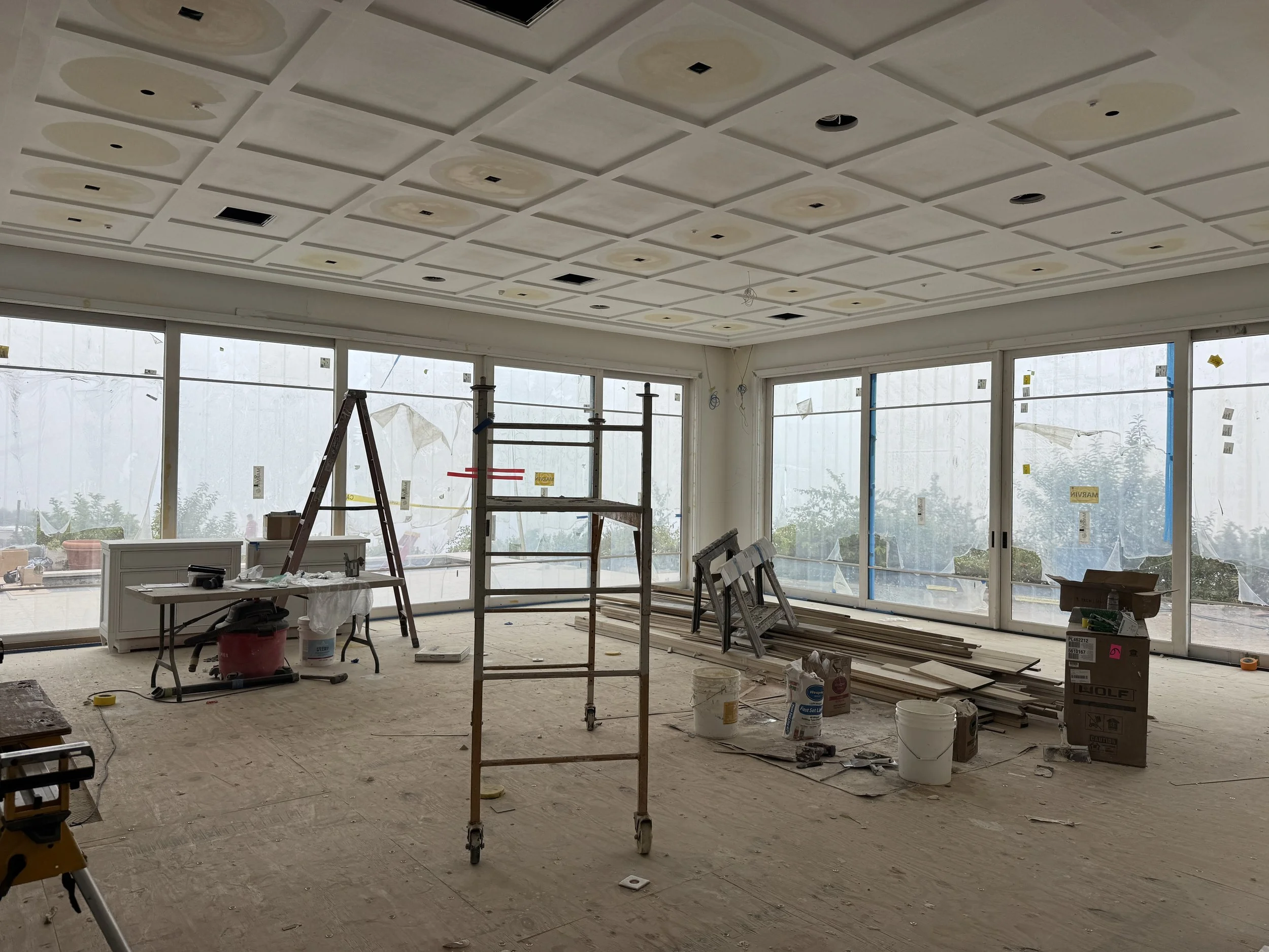 Coffered ceiling during construction, highlighting the detailed architectural millwork and coordination of recessed lighting and mechanical systems.