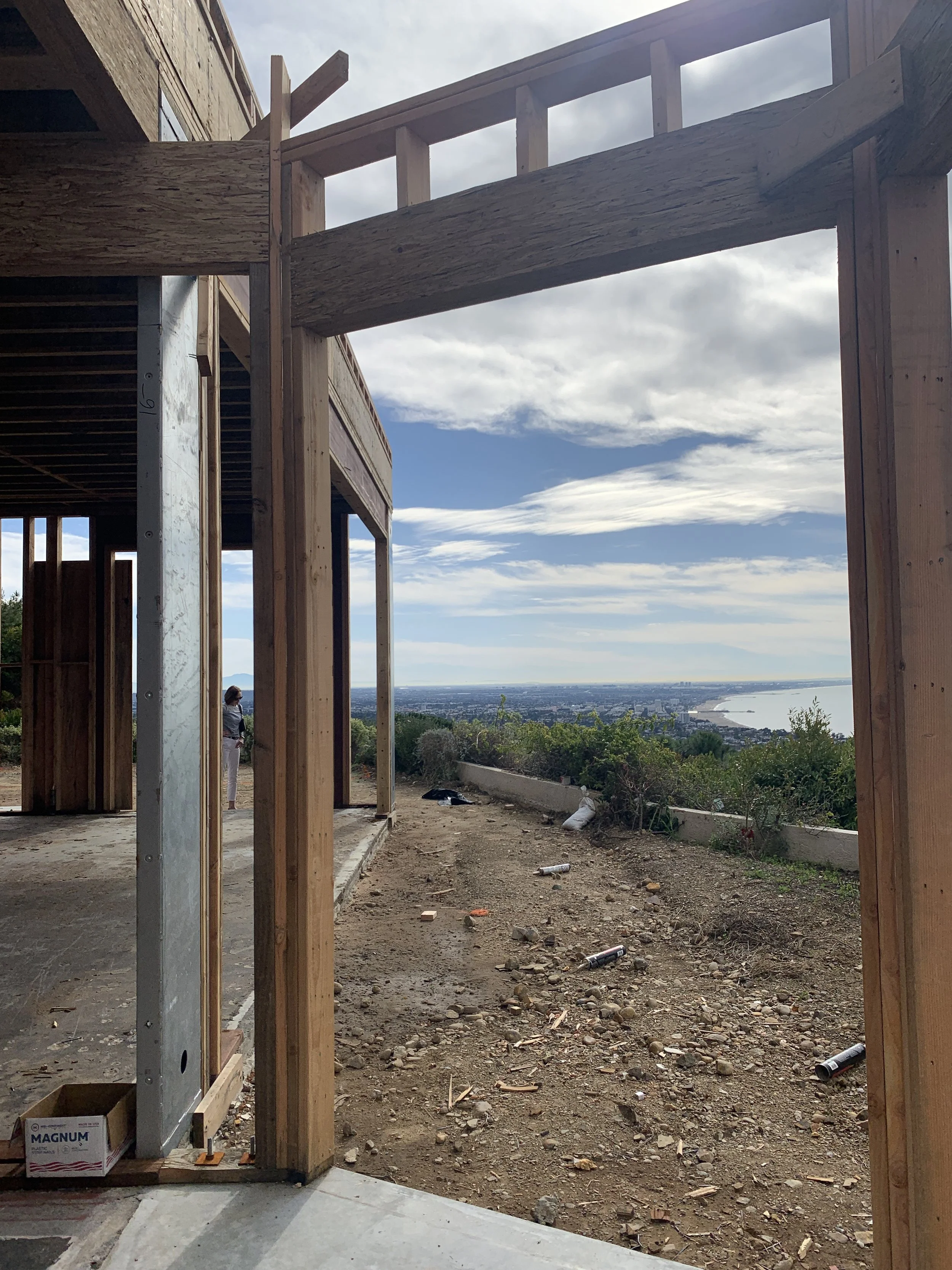 Large framed opening during construction, capturing the relationship between the residence, its hillside setting, and expansive coastal views.